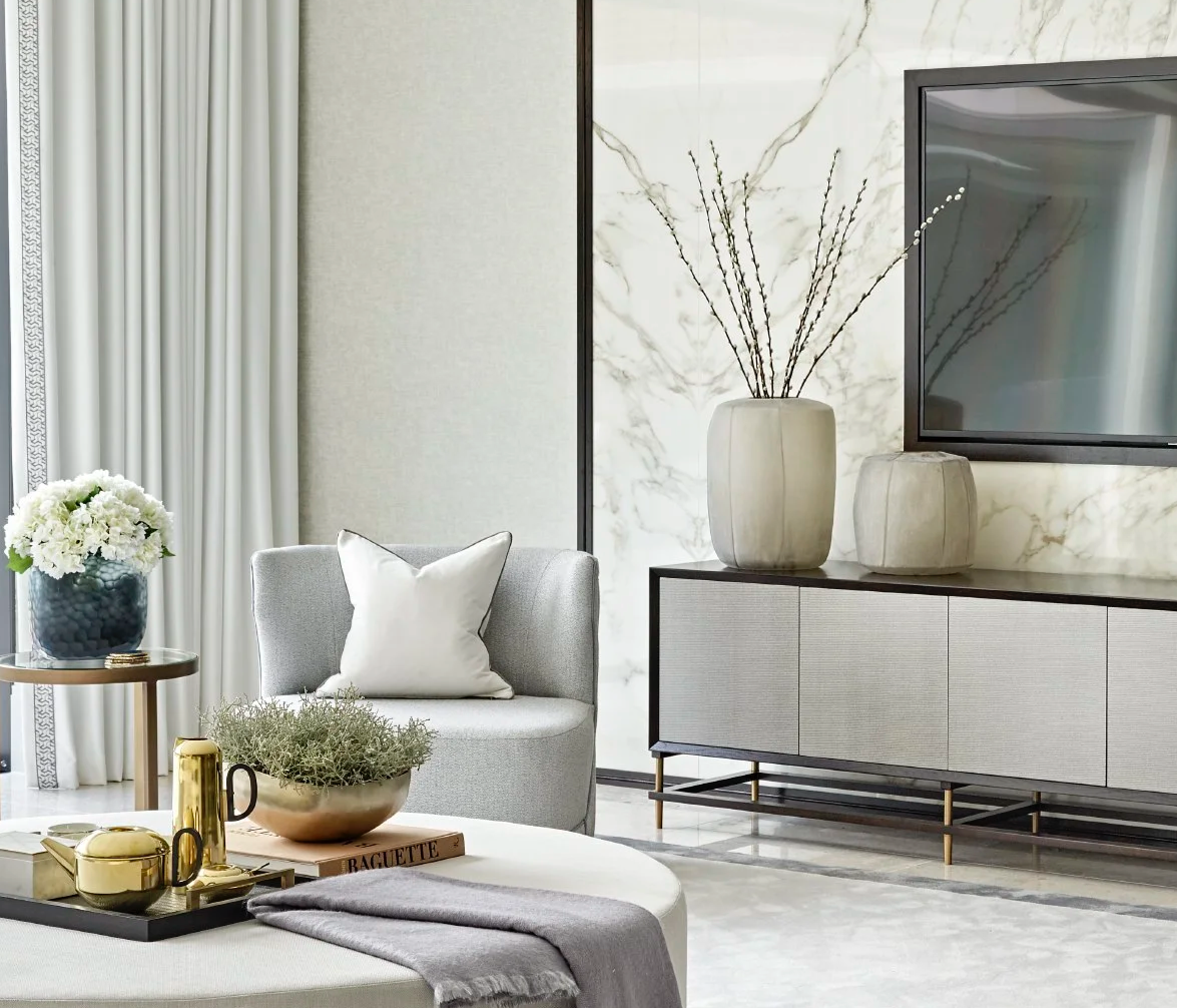 Luxury modern living room styled with neutral furniture, gold accessories, brass accents, and marble TV wall