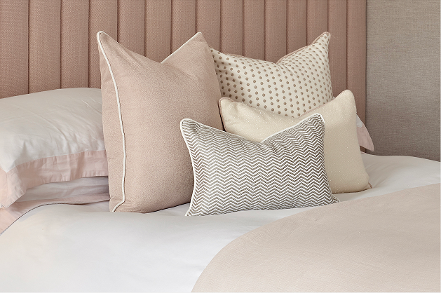 Luxury kids bedroom with pink upholstered headboard and bed styled with multiple decorative cushions in different patterns and sizes