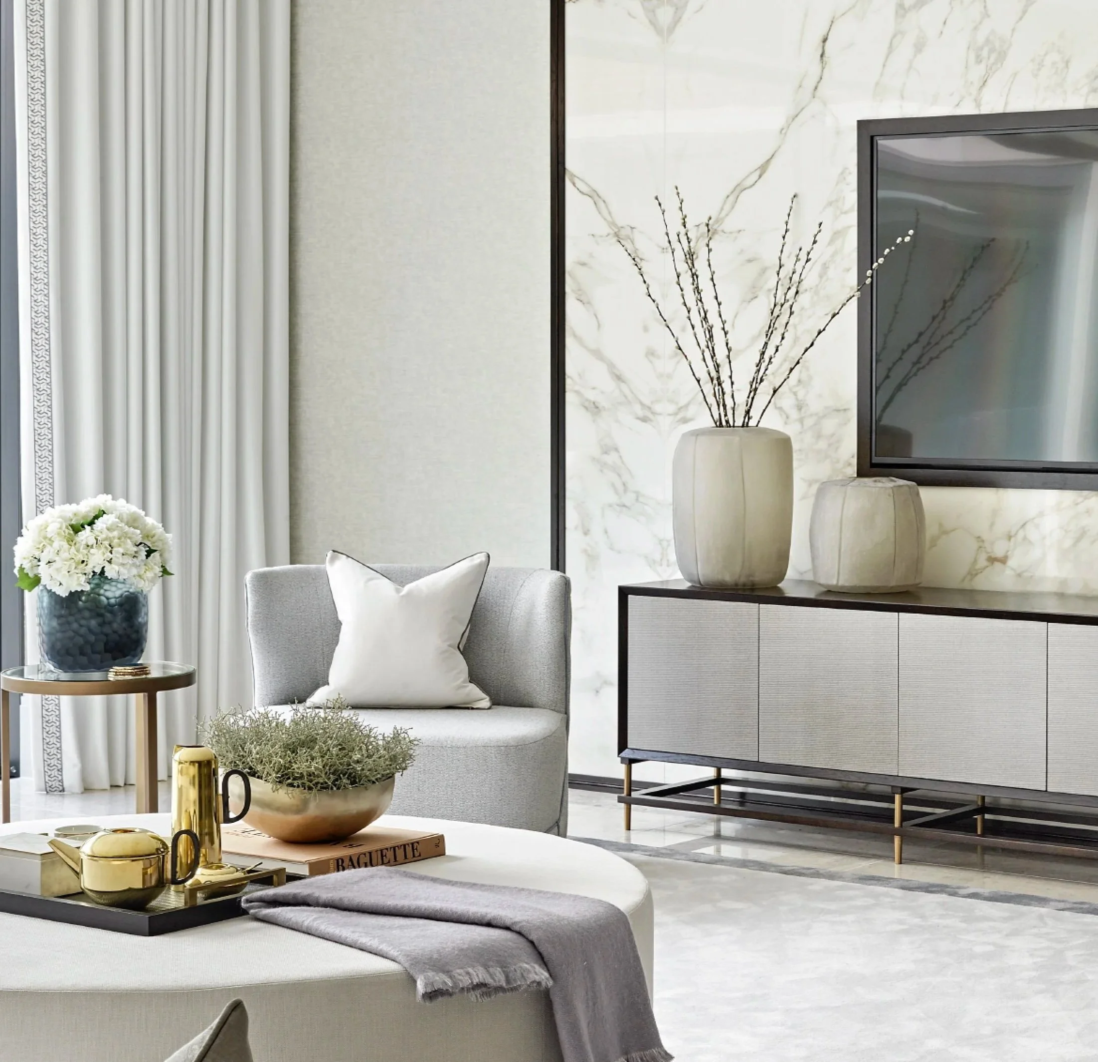 Modern luxury living room with neutral tones, brass details, and a marble accent wall, showcasing interior design services