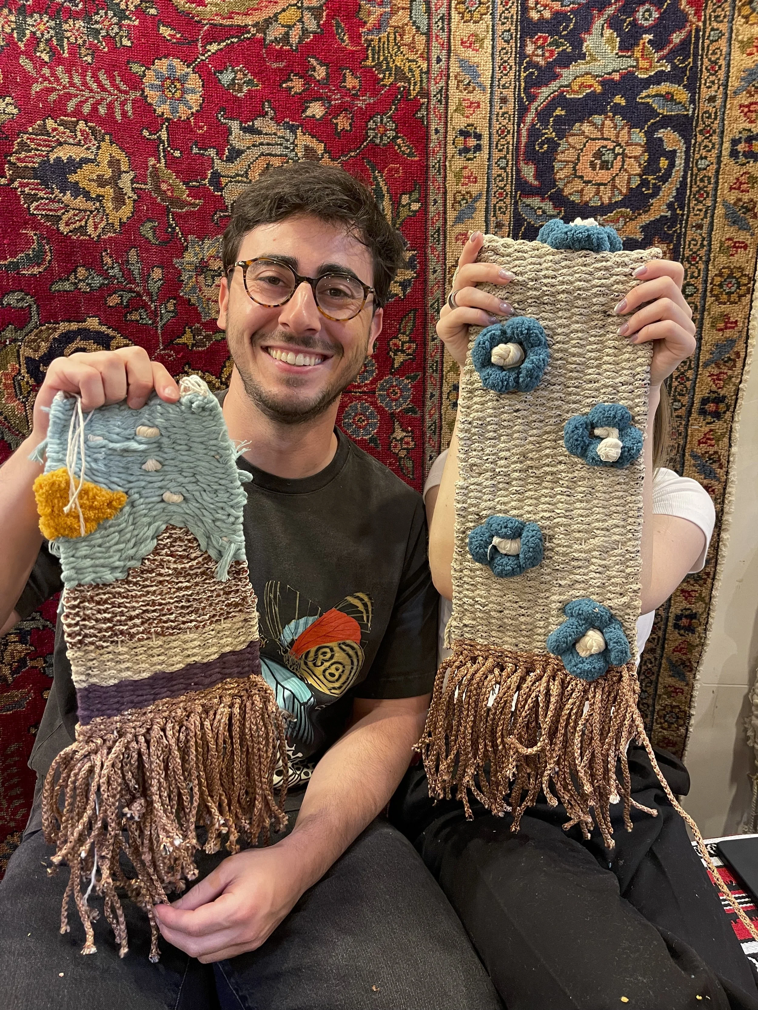 A couple proudly holding their finished hand woven tapestry at one of the largest weaving looms in New York City during a shared creative experience