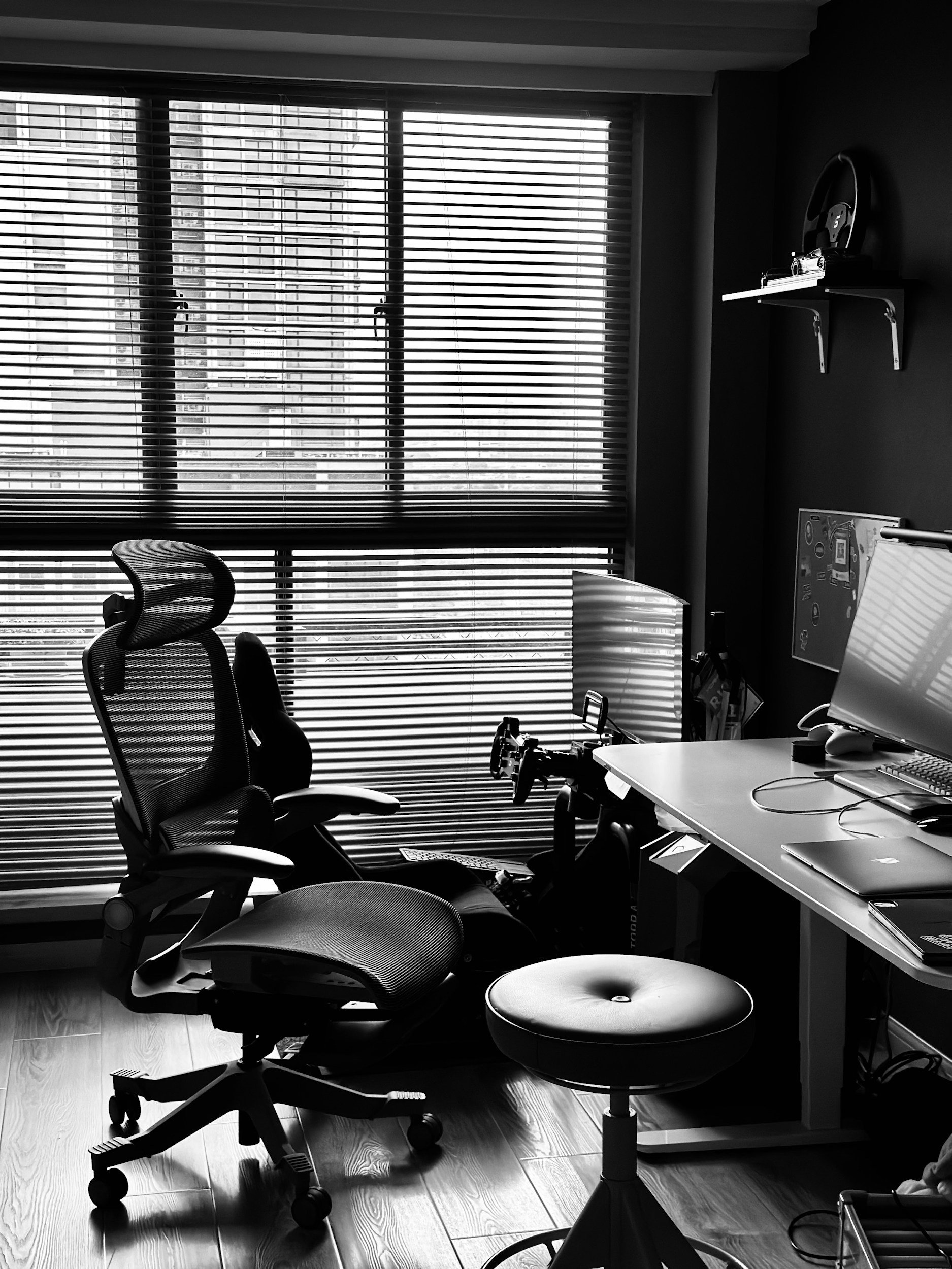 A home office with a large window with blinds, an ergonomic office chair, a desk with a computer monitor, laptop, and various items you'd find in an office. Indicative of typical WNY small businesses that need bookkeeping.