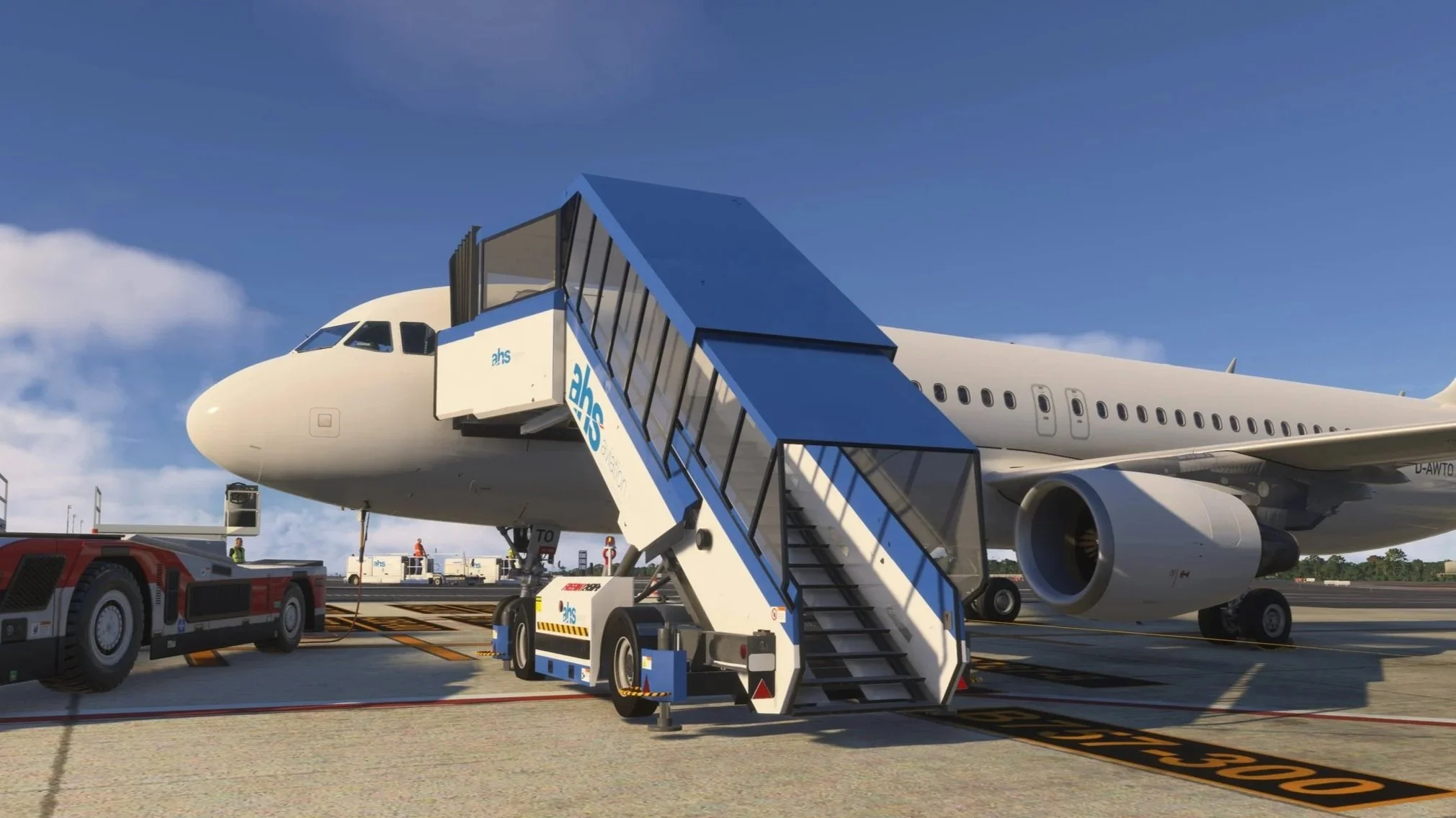 An airplane at an airport gate with a stairs attached, ground crew, and airport vehicles nearby.