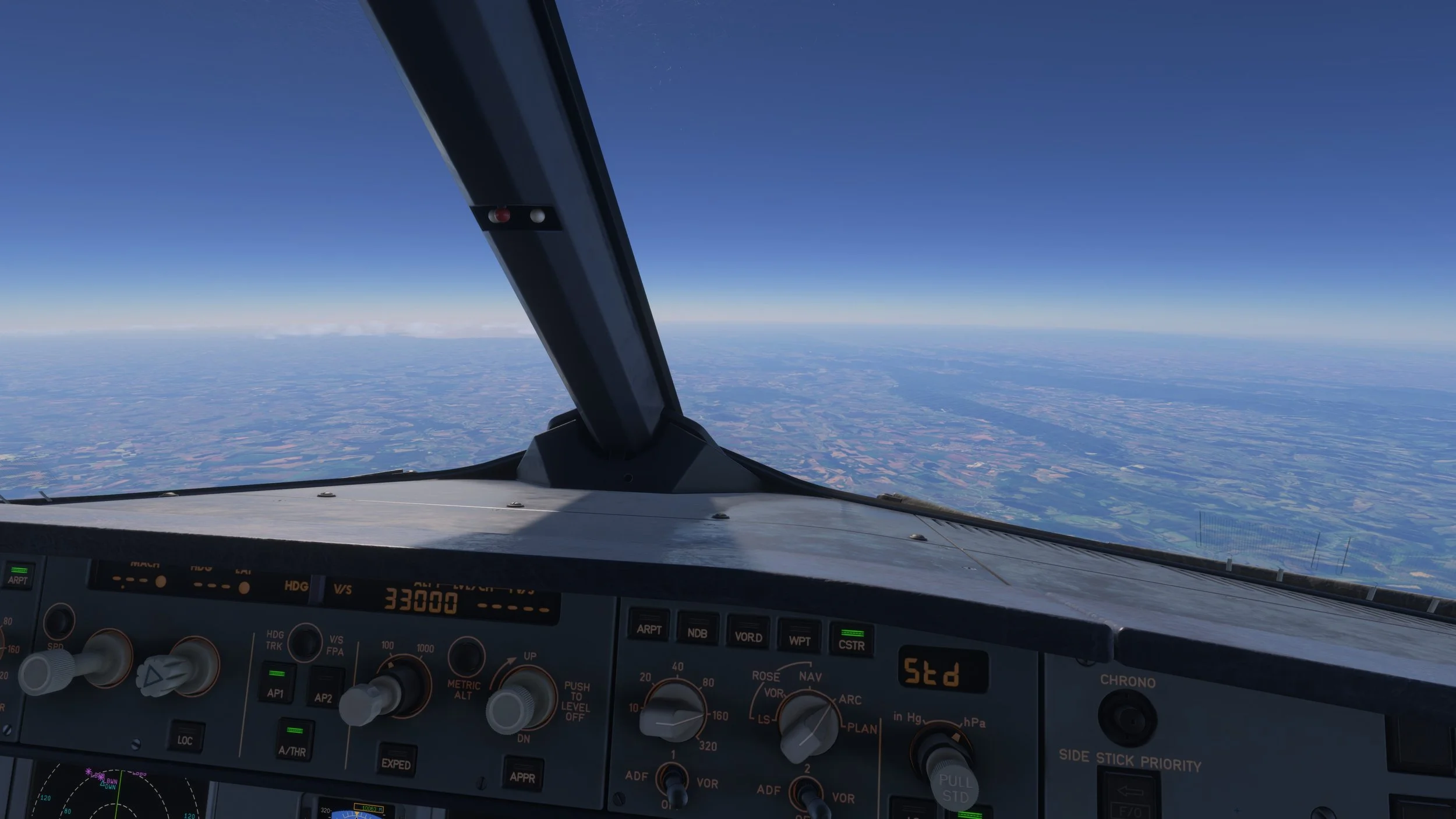 View from an airplane cockpit showing the aircraft's instruments dashboard and a clear sky with clouds and land below.