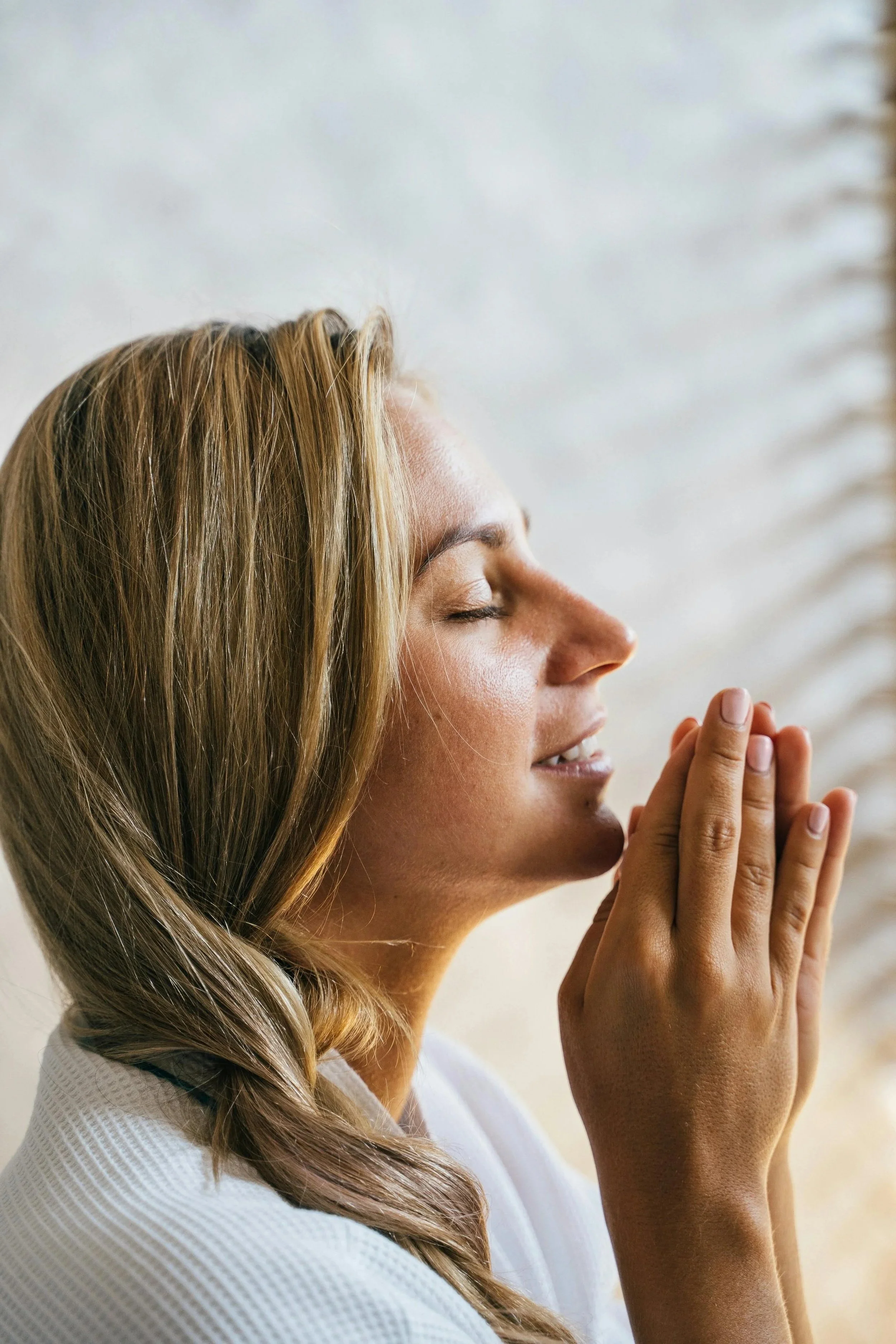 A woman, her eyes cosed, smiling with quiet joy as she does breathwork.