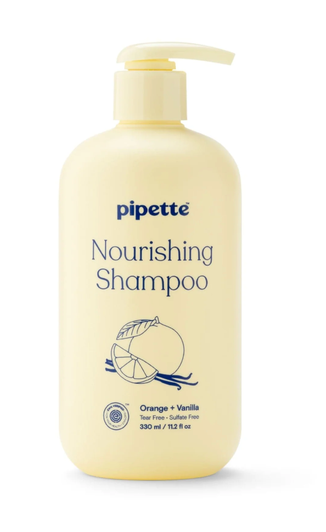 A bottle of pipette nourishing shampoo with orange and vanilla scent, featuring a pump dispenser, cream color, and label with illustrations of orange and vanilla.