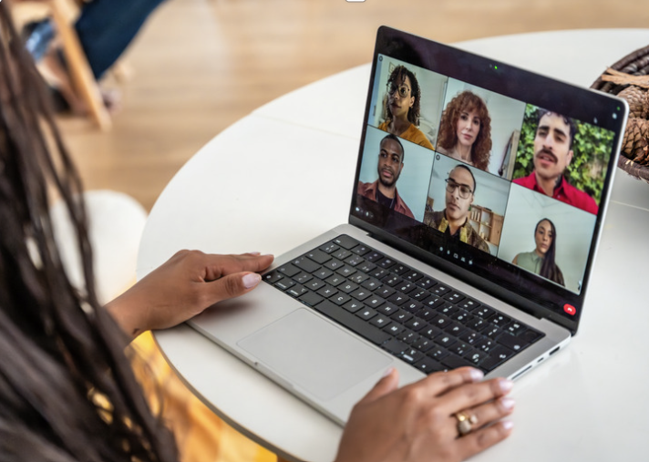A professional joins a virtual meeting with a group of colleagues on her laptop.