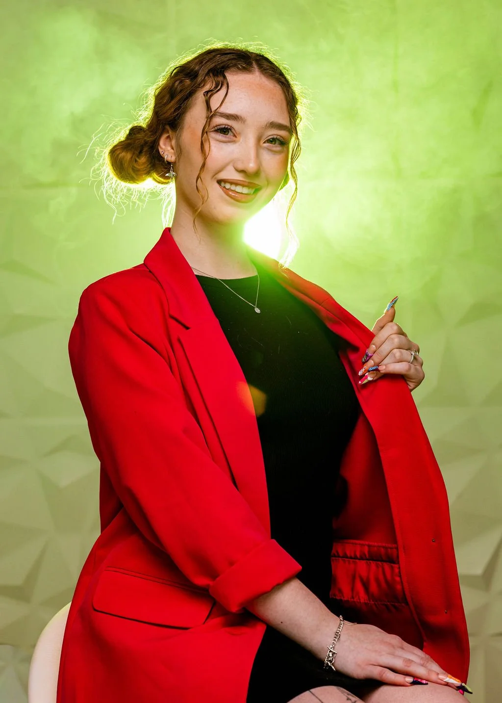 Headshot of Indy smiling at the camera wearing  