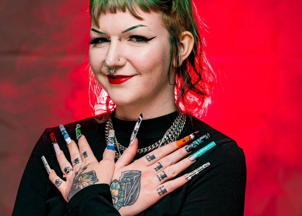 Headshot of Jaycee smiling at the camera and showing off her nails