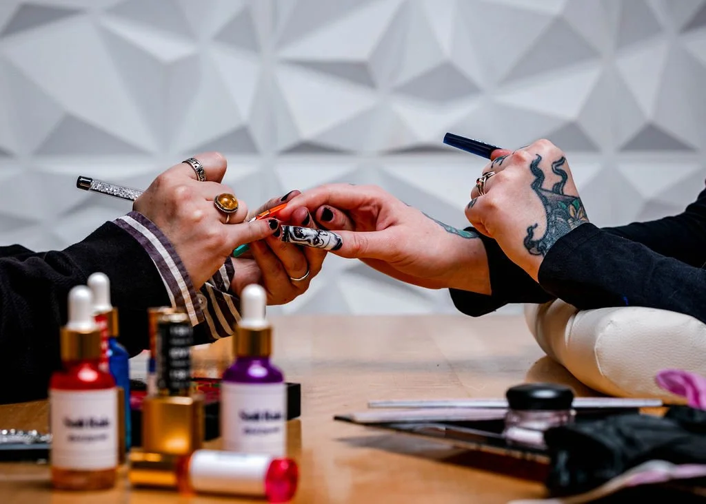 nail tech adds finishing touches to a set of long nails