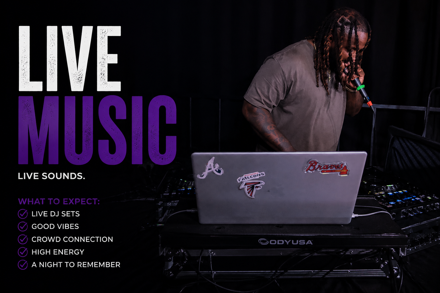 A DJ with dreadlocks using a microphone at a live music event, with a laptop displaying stickers of sports teams.