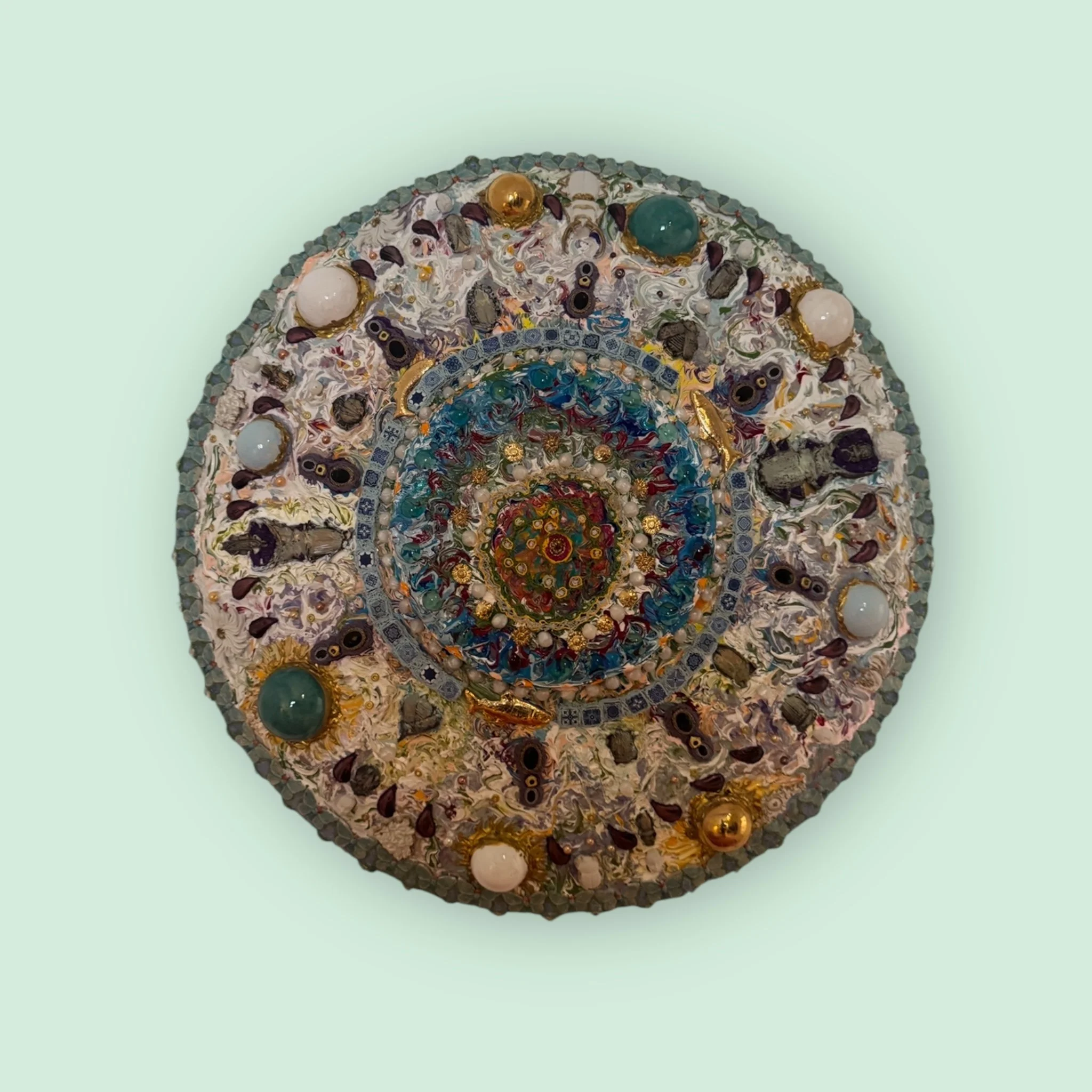 Kreisförmiges, kunstvolles Objekt mit bunten Glas- und Perlenakzenten, auf einem hellen Hintergrund.