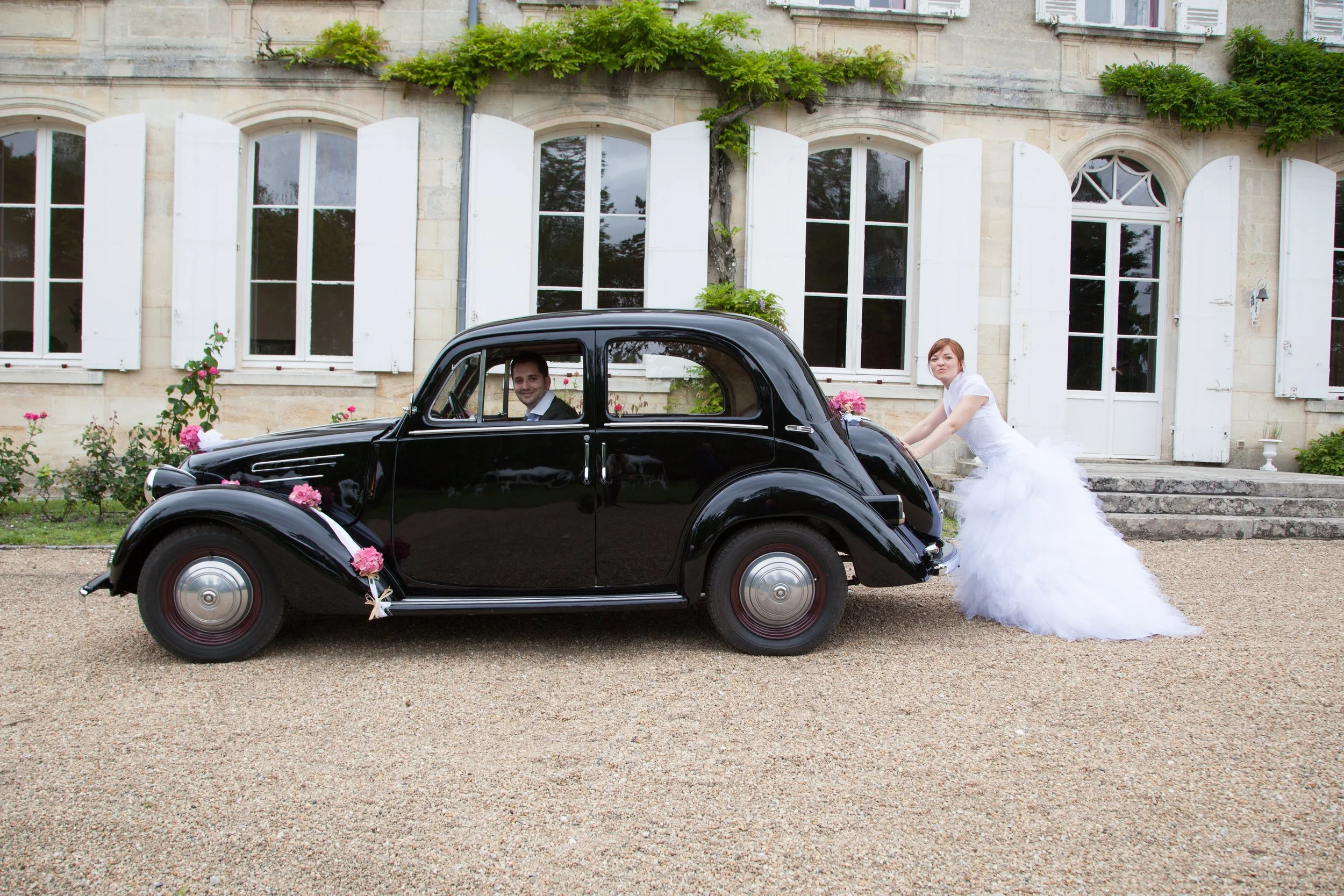 Bride and Groom Messing with wedding car