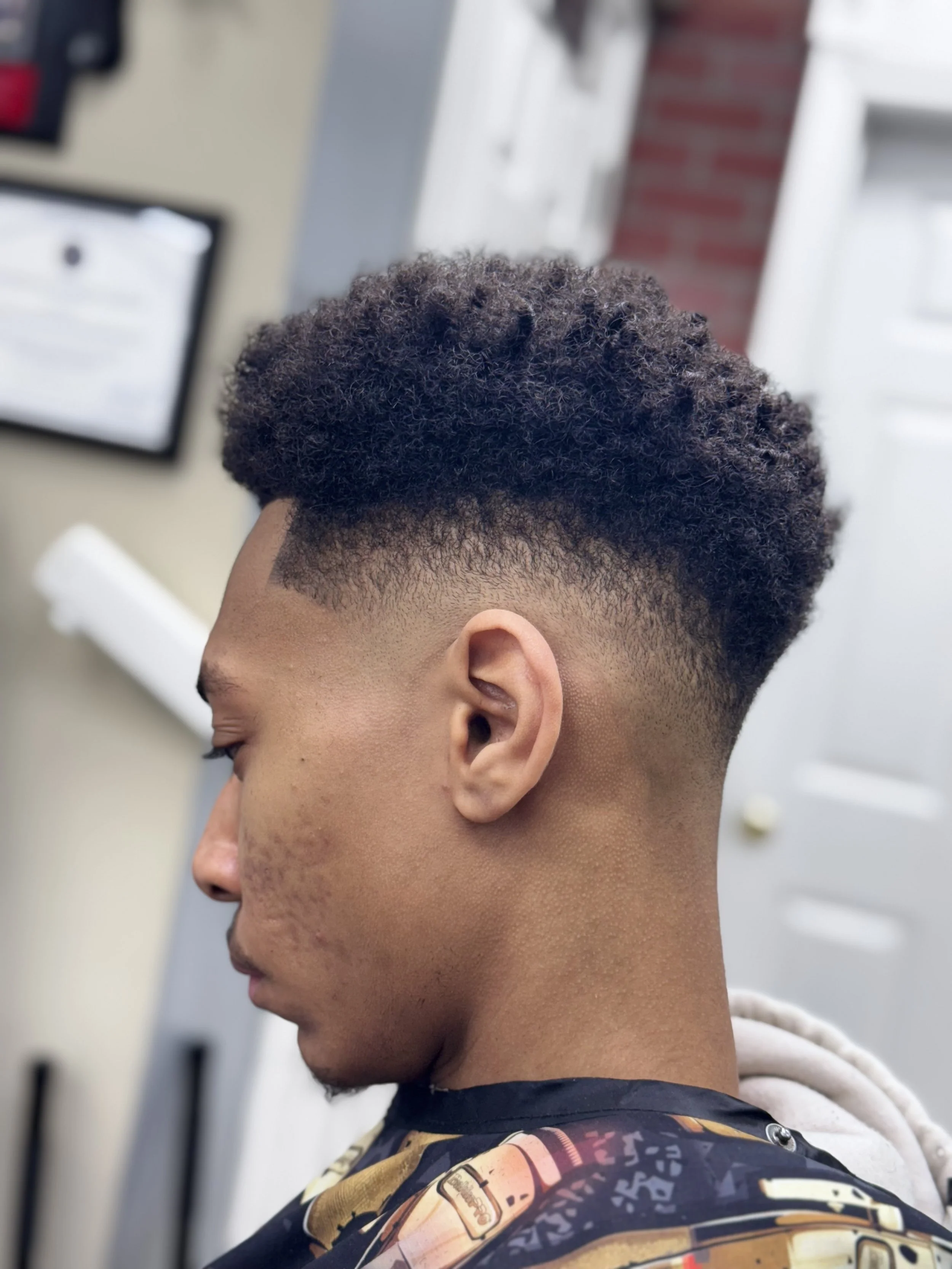 Young man with a high fade haircut getting a haircut at a barber shop.