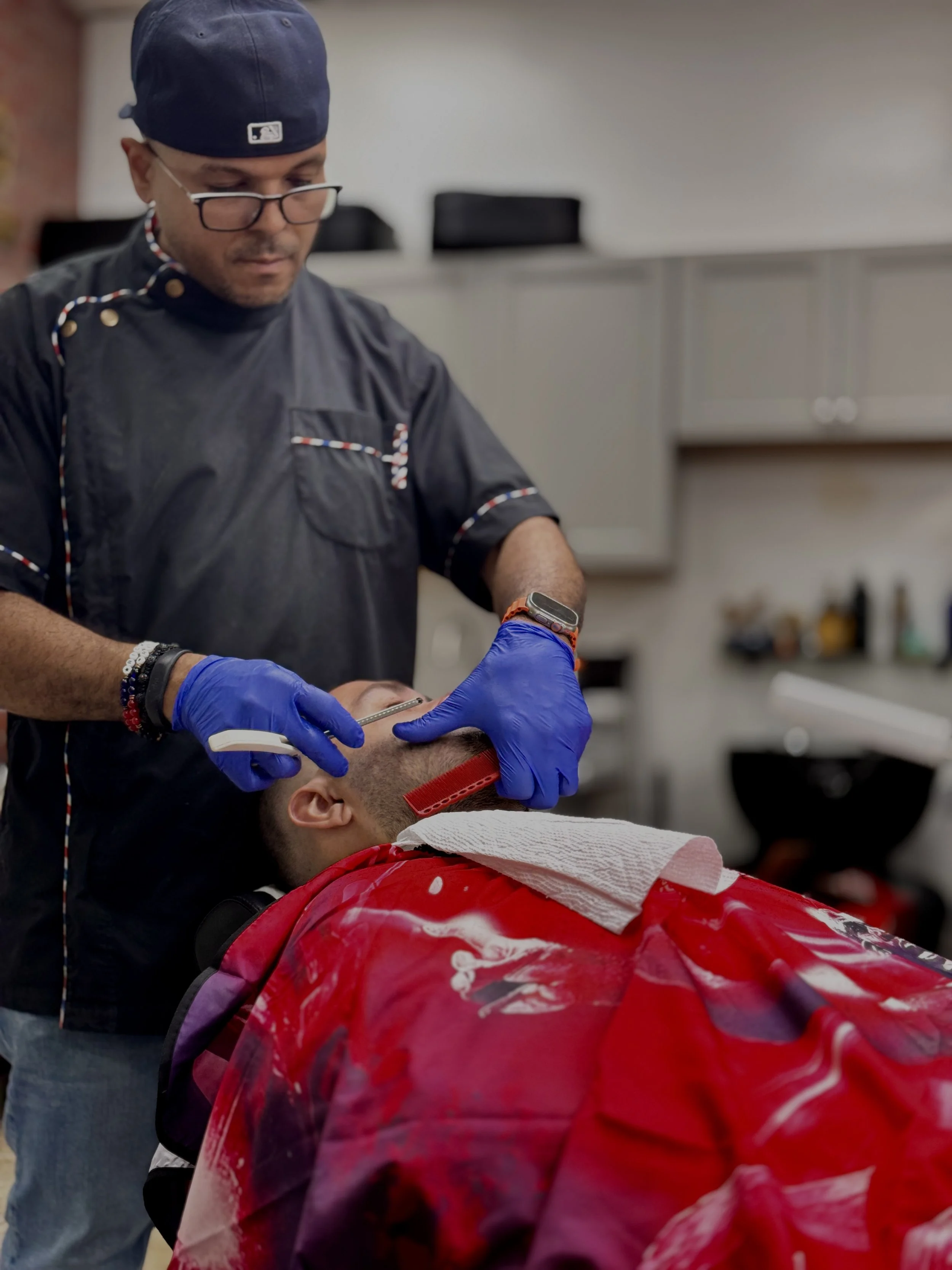 A barber shaving a man's face in a barbershop.