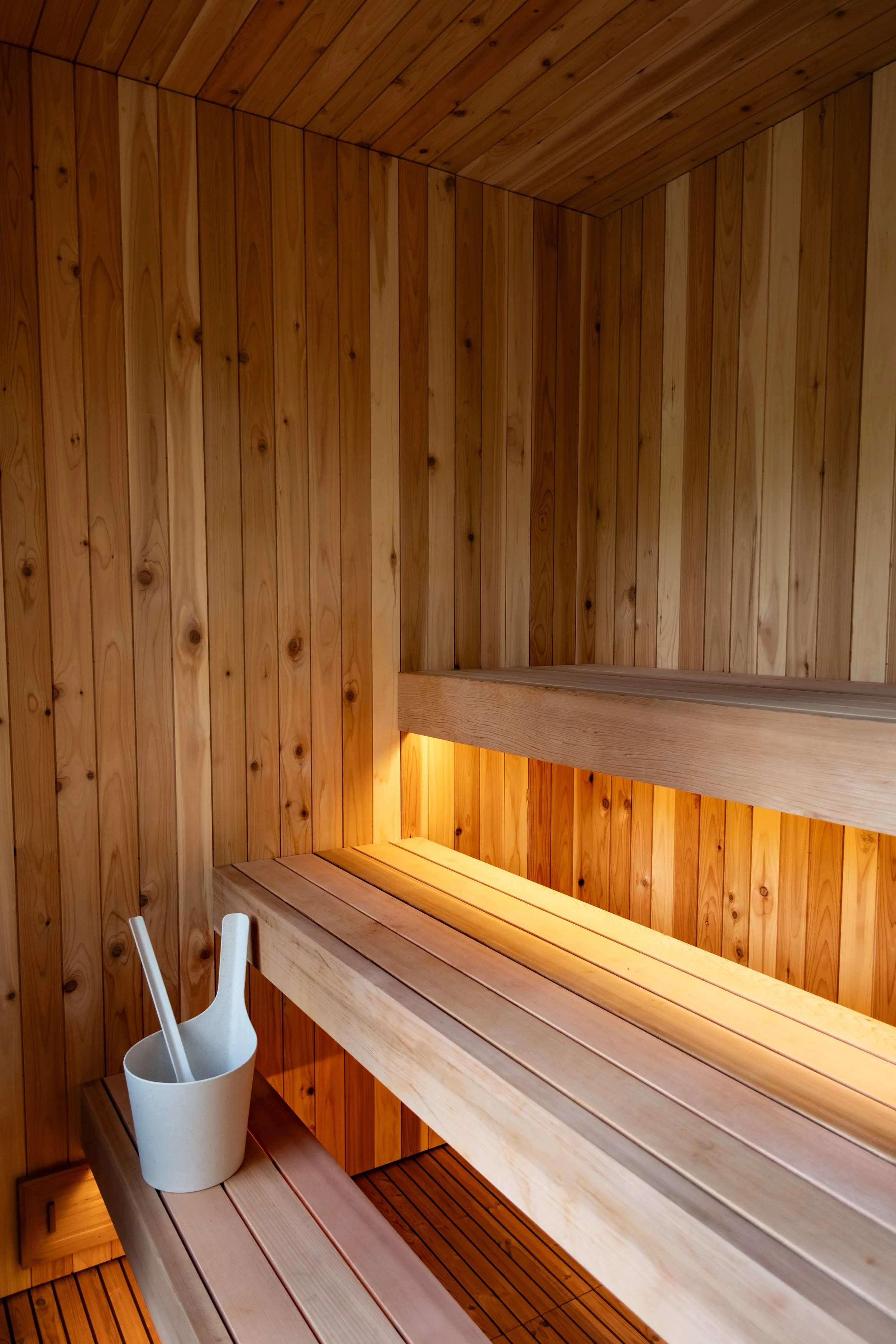 Inside a traditional Finnish sauna with wooden walls, benches, and a bucket with a ladle.