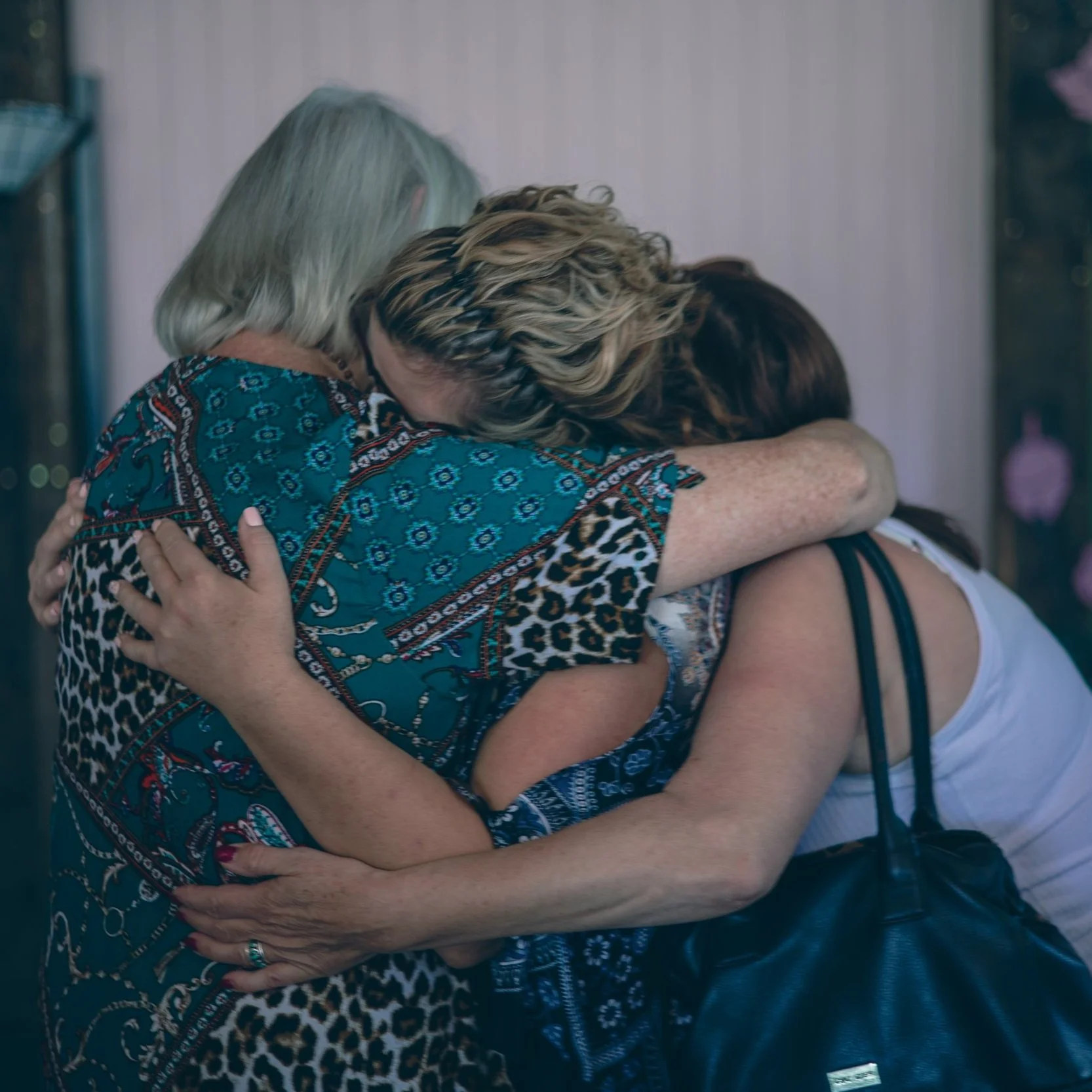 Three women hugging tightly, expressing strong emotions.