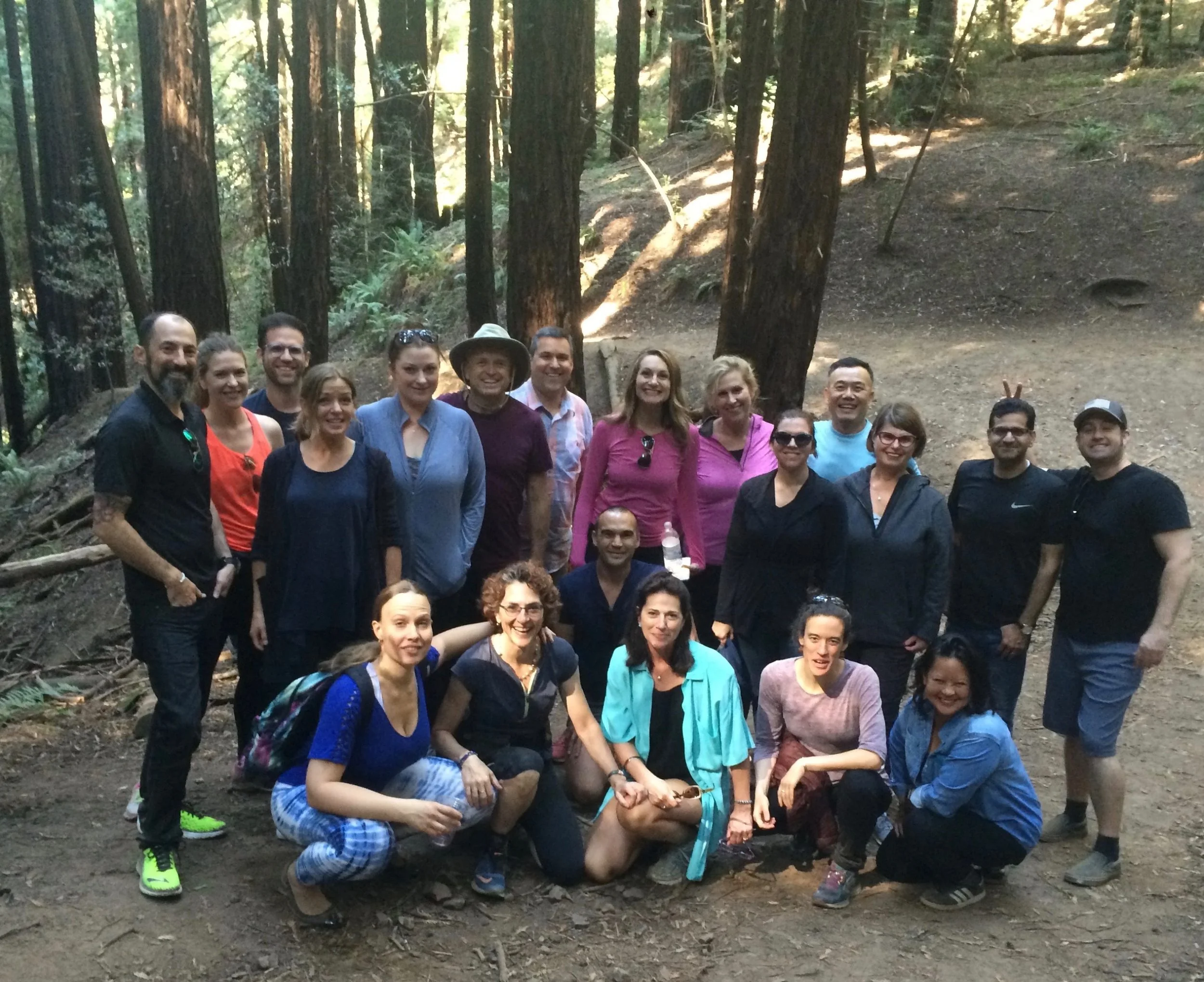 Group of people in a forest, smiling and posing for a photo.