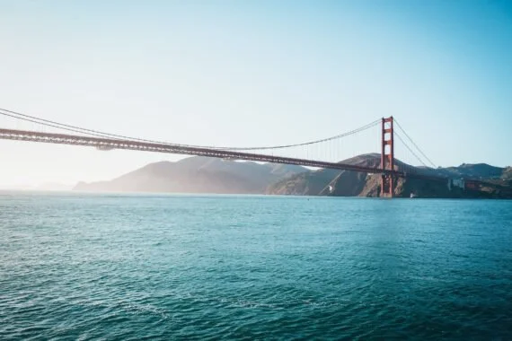 View of the Golden Gate Bridge over the water with a mountain in the background.