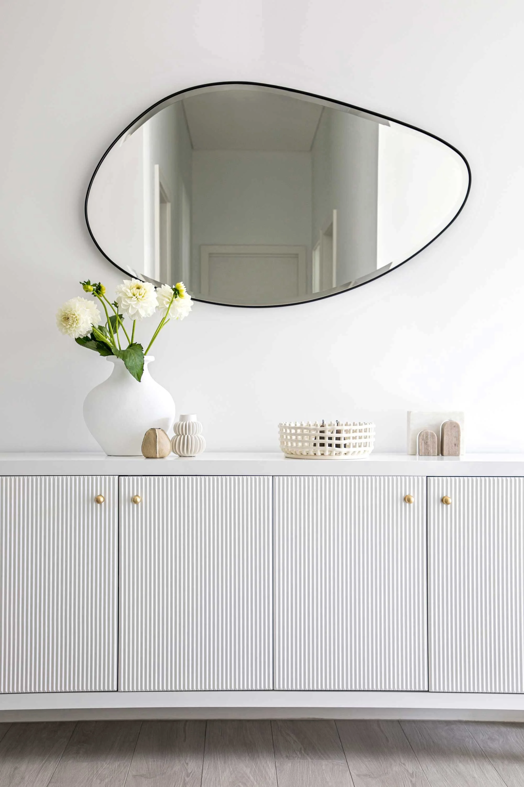 Hall sideboard with bubble shaped mirror on wall flowers and vase NSW South Coast