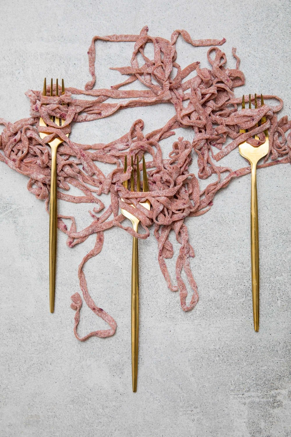 Spaghetti pasta shaped like the map of the United States, with three gold forks placed on different regions.