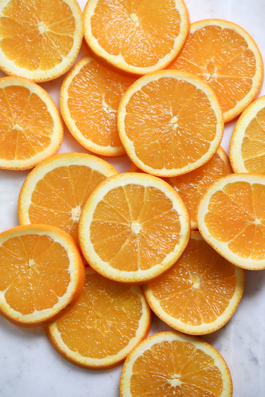 Several orange slices scattered on a white surface.