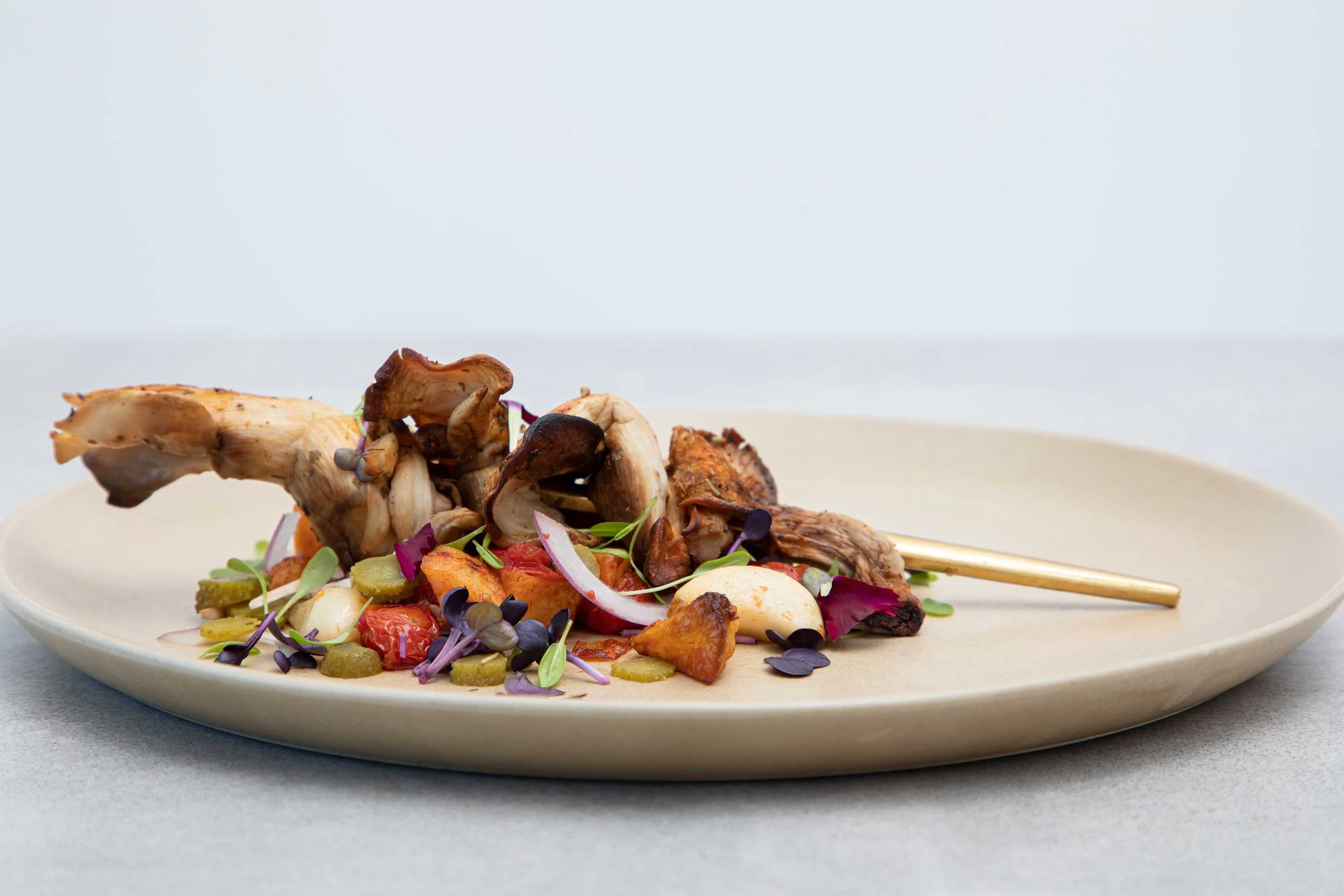 Roasted chicken and vegetables on a white plate, garnished with microgreens.