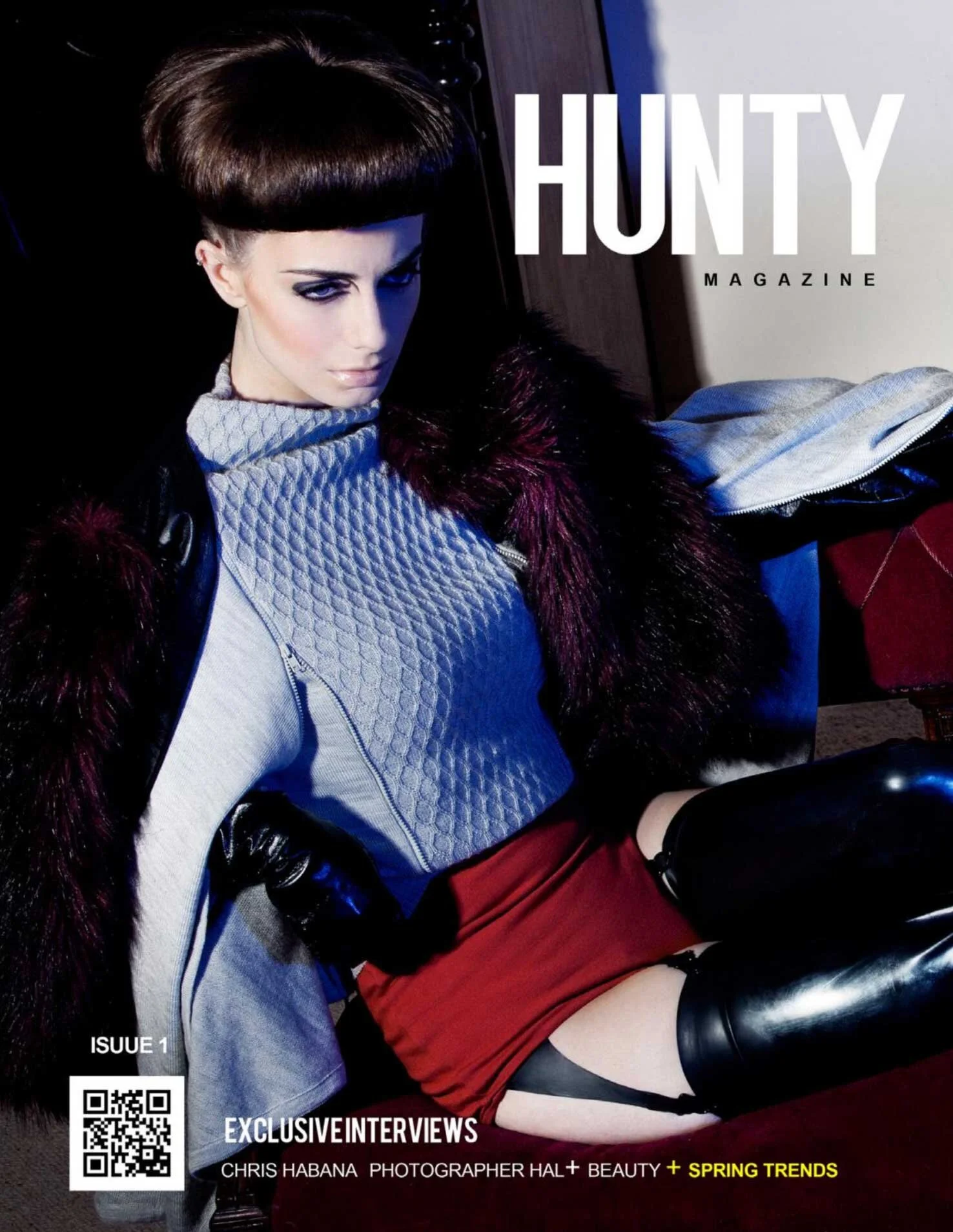 Cover of Hunty Magazine featuring a woman with dark, voluminous hair styled in an avant-garde fashion, wearing a light gray textured top, burgundy shorts, and thigh-high black leather boots. The magazine includes headlines about exclusive interviews 