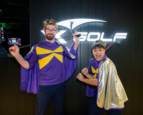 two people with golf clubs smile. they are wearing starlight childrens charity outfits.