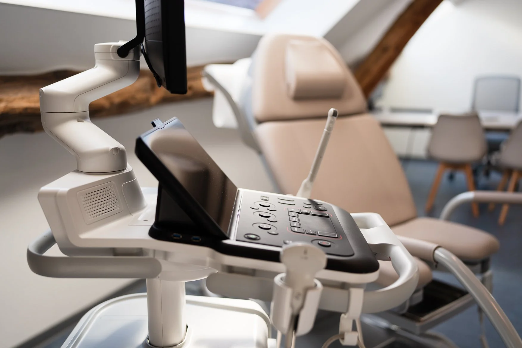 Medisch echografie apparaat met monitor en probe in een medische kamer met beige stoelen.