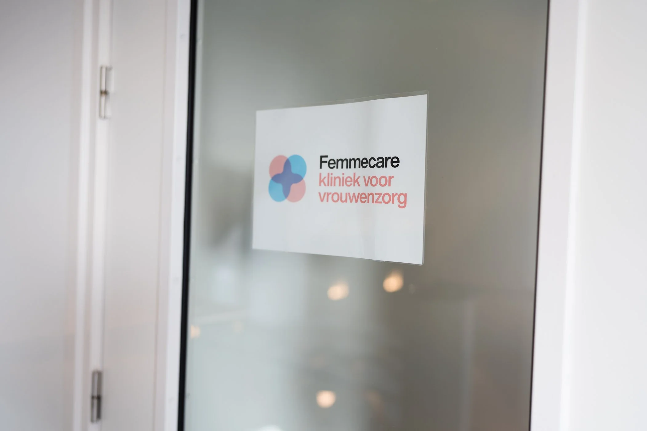 Raammet deur met sticker van Femecare kliniek voor vrouwenzorg.