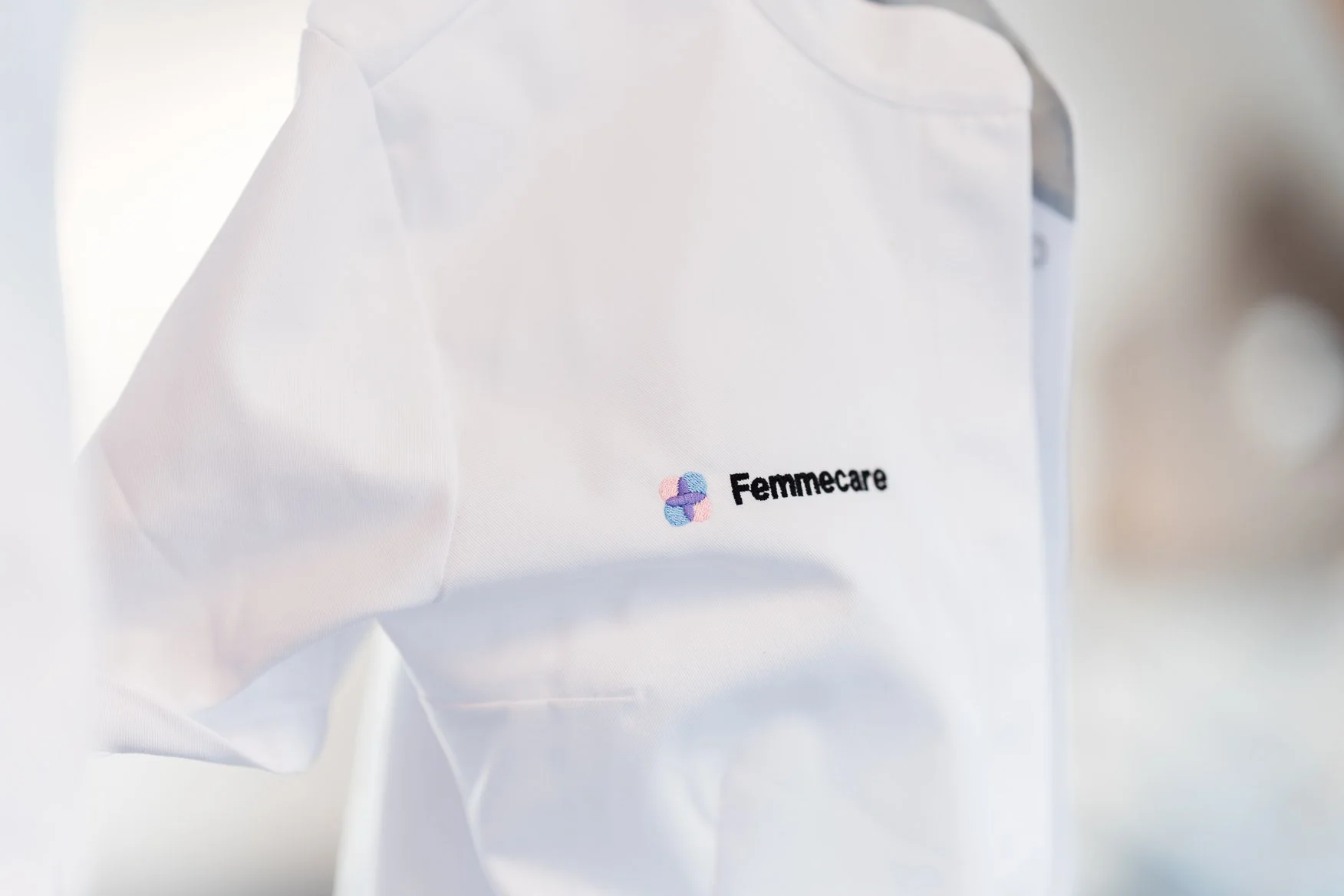 Een witte naaimachine met het logo en de naam 'Femmecare' op de zijkant.