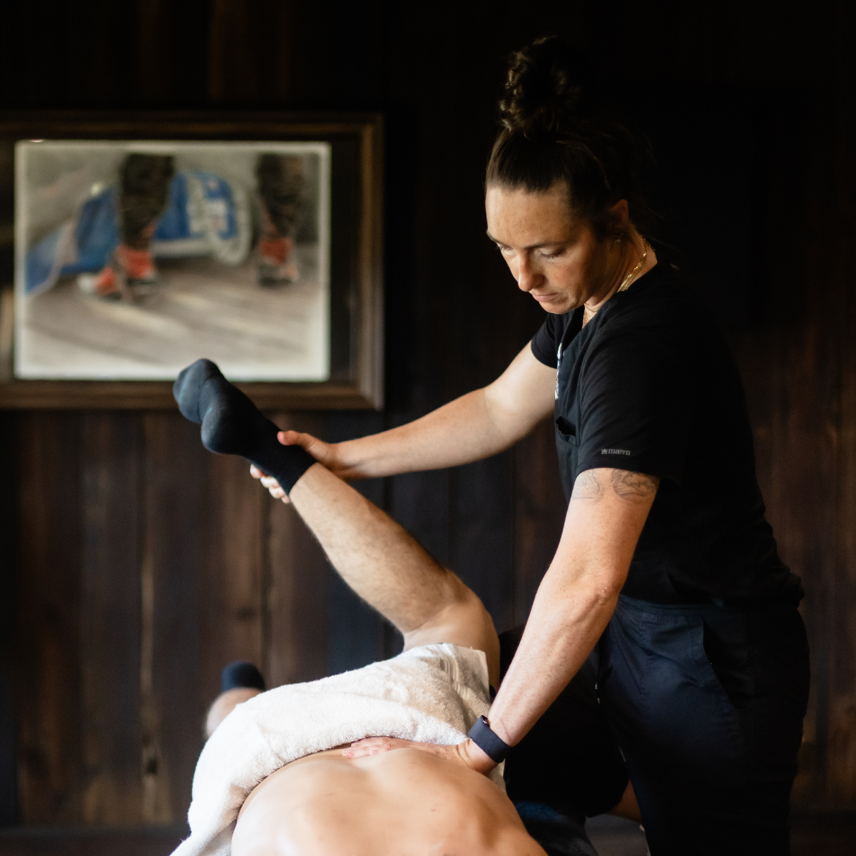 An athlete receiving a massage or physical therapy treatment in a dimly lit room.