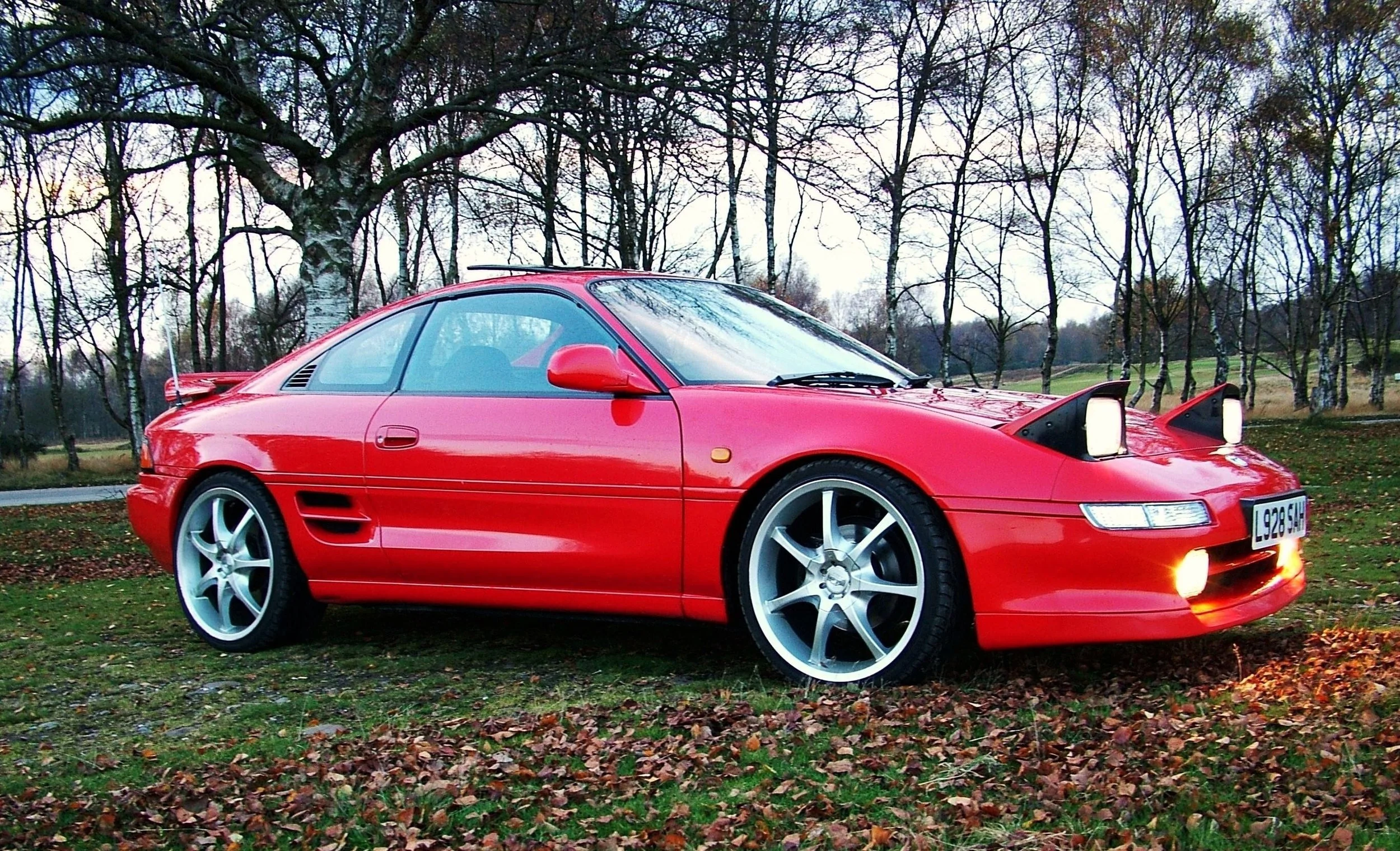 Toyota MR2 in field with leaves on the ground