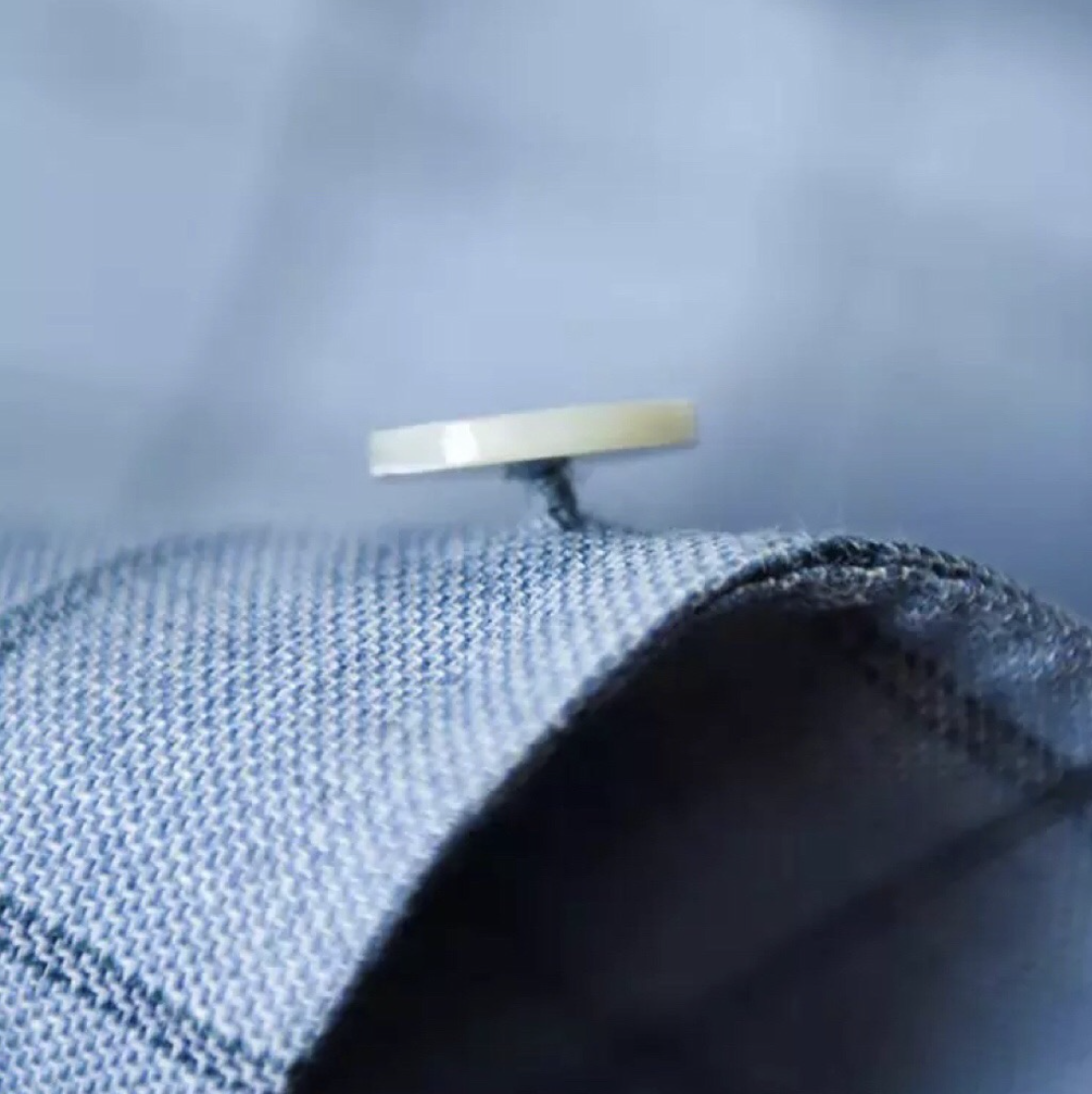A sewing machine needle stitching blue denim fabric.