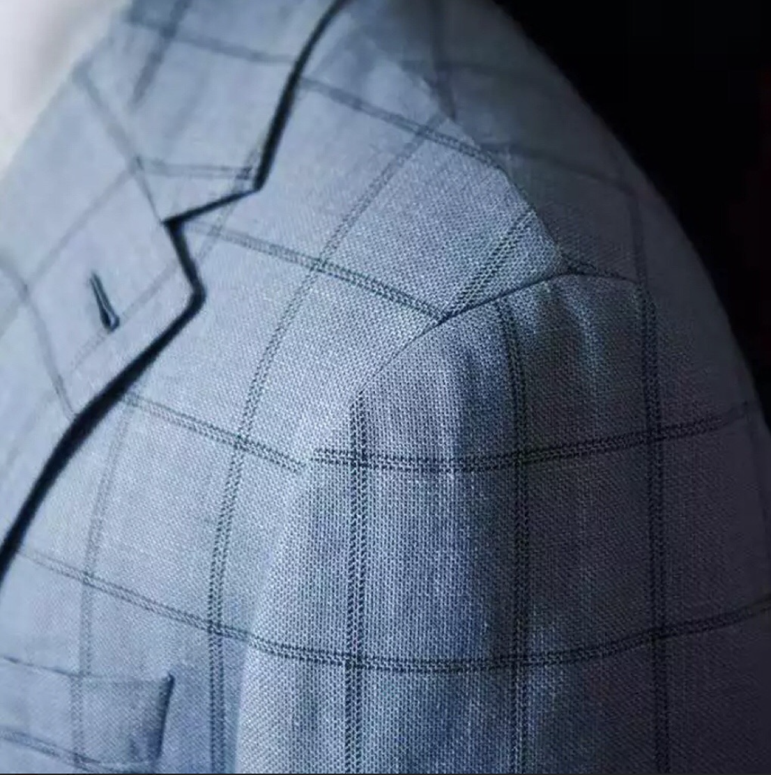 Close-up of a fabric with a plaid pattern, showing fine lines and checkered design.