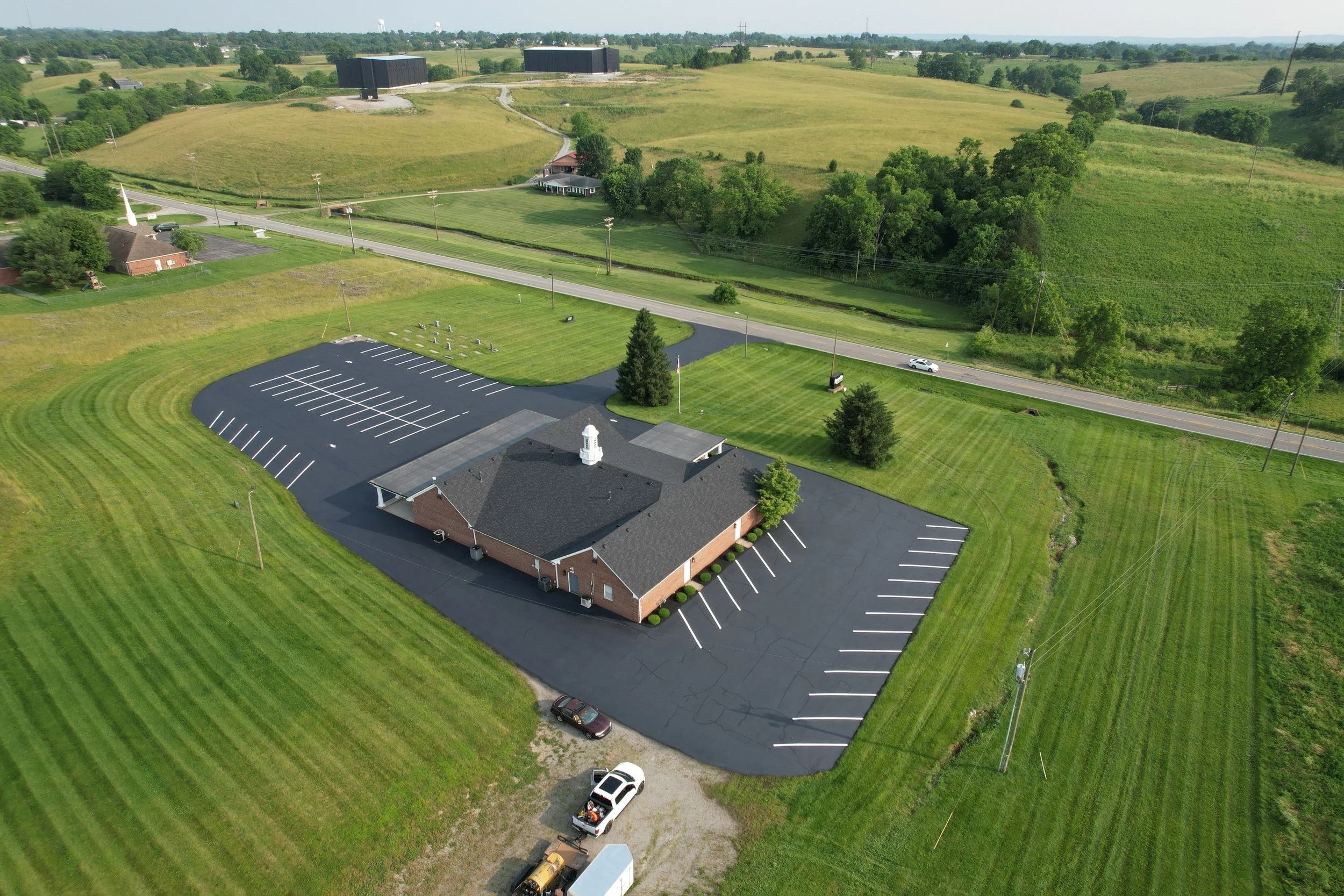 A large parking lot with newly painted white lines, some Asphalt repairs and sealcoat 