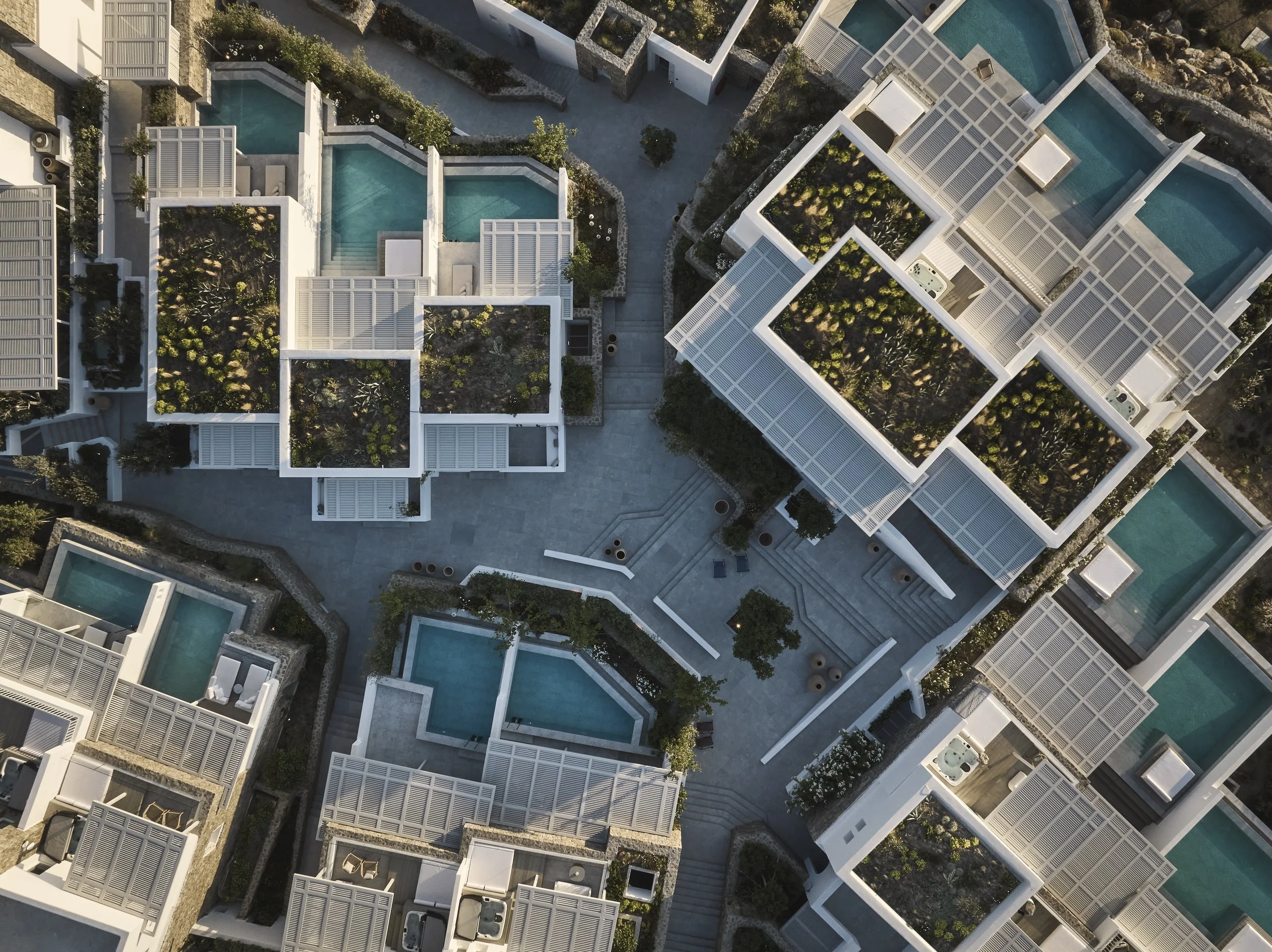 Aerial view of a modern apartment complex with multiple pools, rooftop gardens, and landscaped pathways.