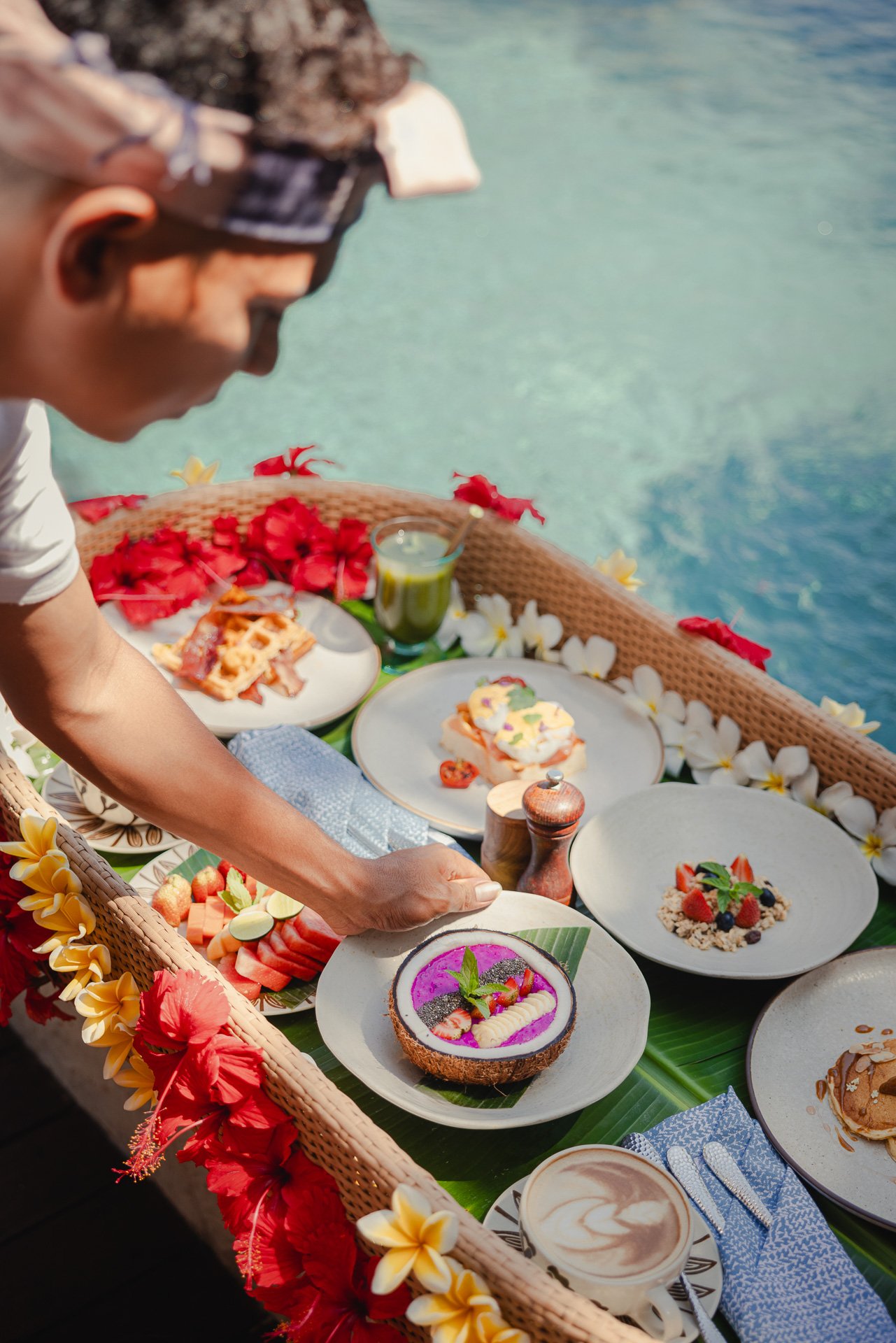 Desserts and drinks by the water, surrounded by flowers.