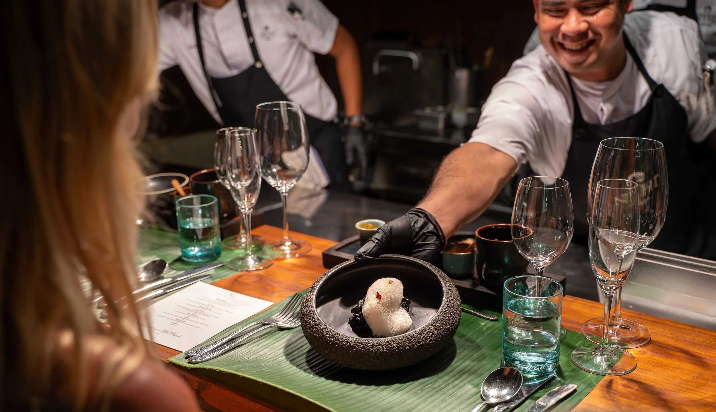 A chef serving a dessert to a guest.