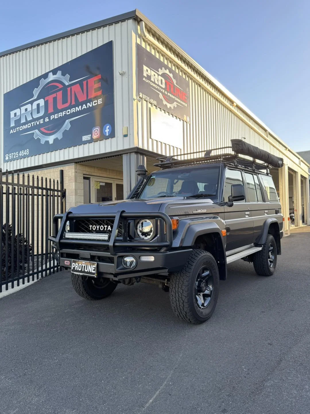 A gray Toyota Land Cruiser parked outside a building with Pro Tune Automotive & Performance signage.