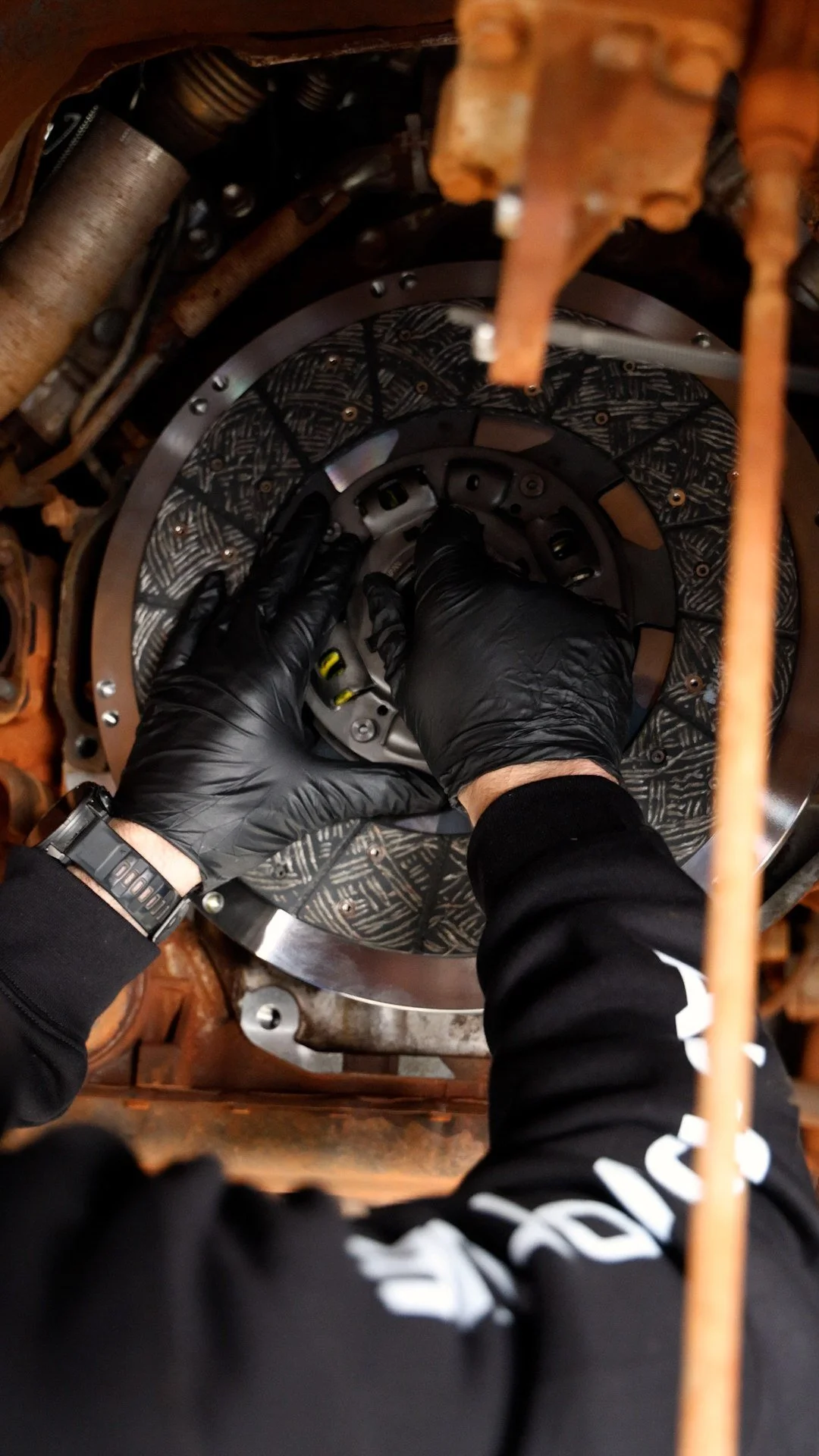 A person wearing black gloves and a black watch working on a mechanical circular component of a land cruiser at Protune in Bunbury.