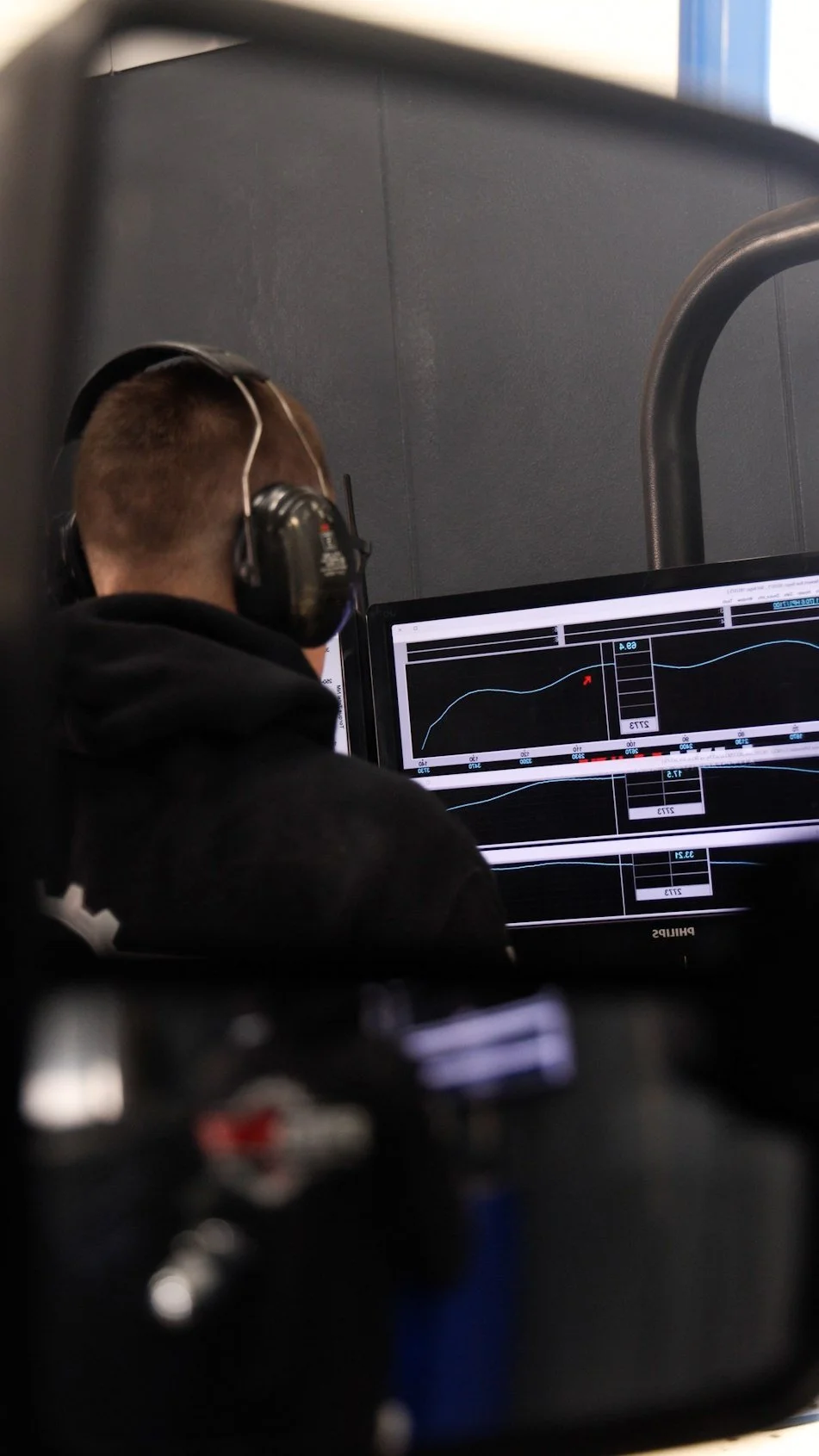 Person wearing headphones working on a computer with graphs and data on the screen.