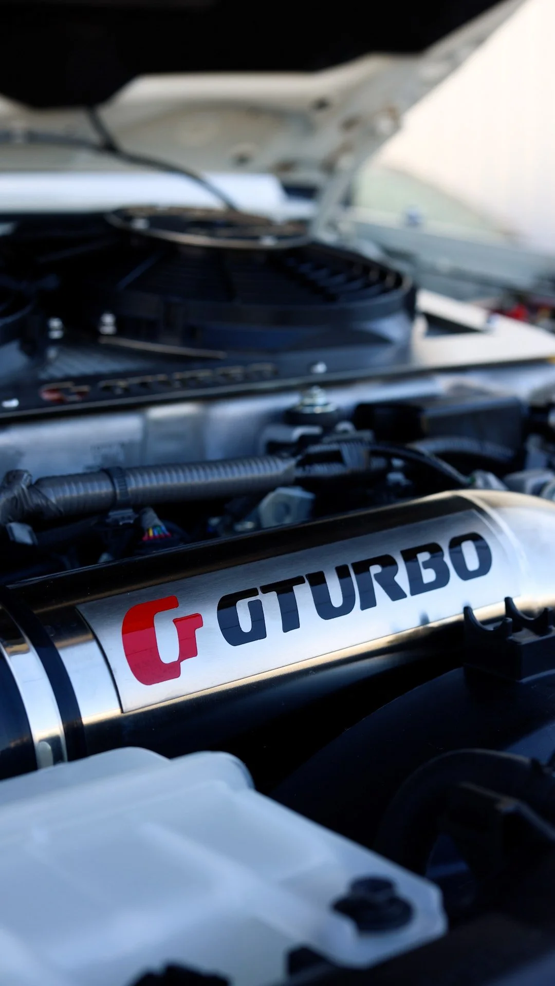 Close-up of a turbocharger with the word 'TURBO' and a red logo on it inside a car engine bay.