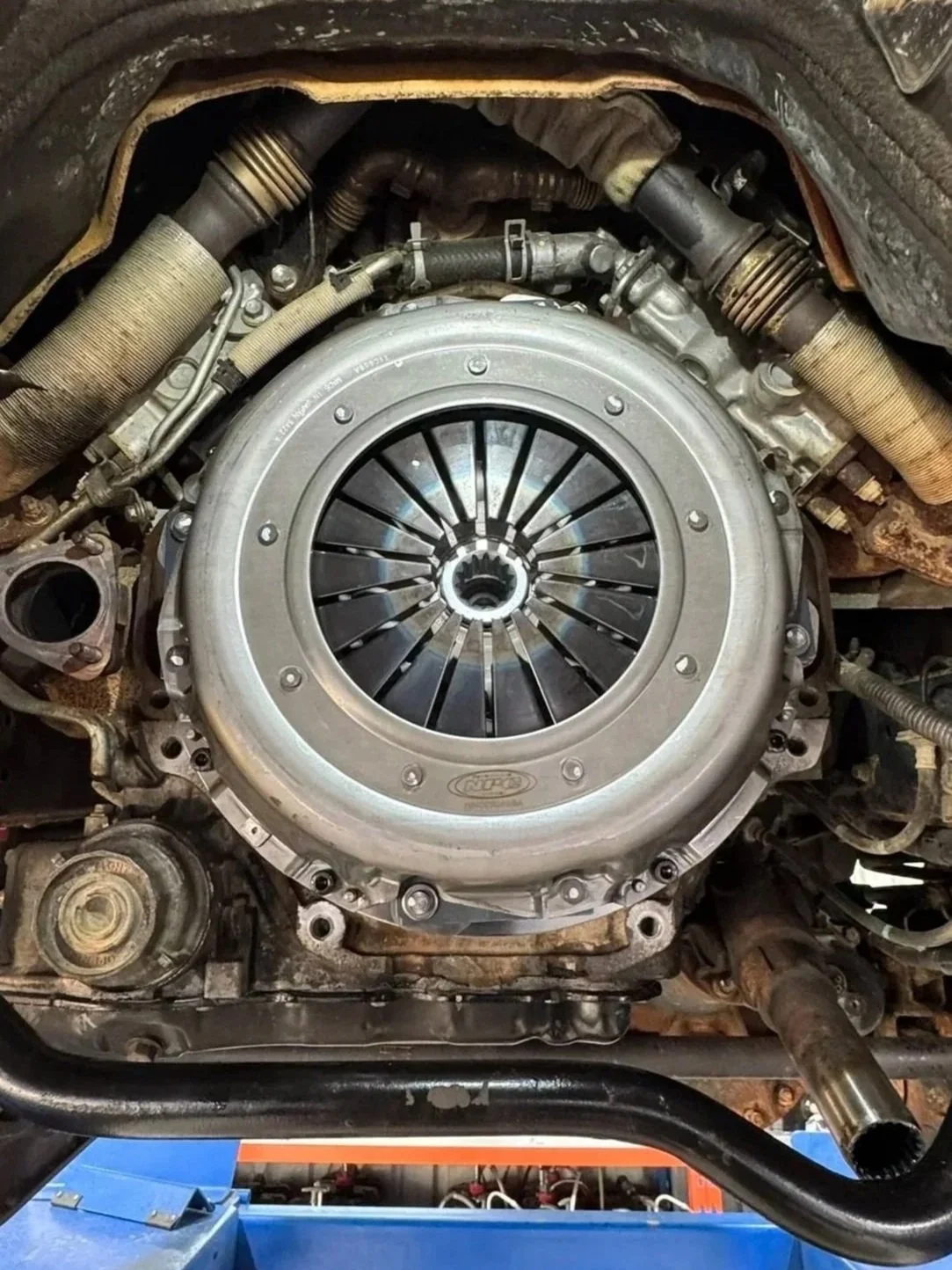 Close-up view of a car engine's clutch assembly with visible clutch disc, pressure plate, and surrounding engine components.