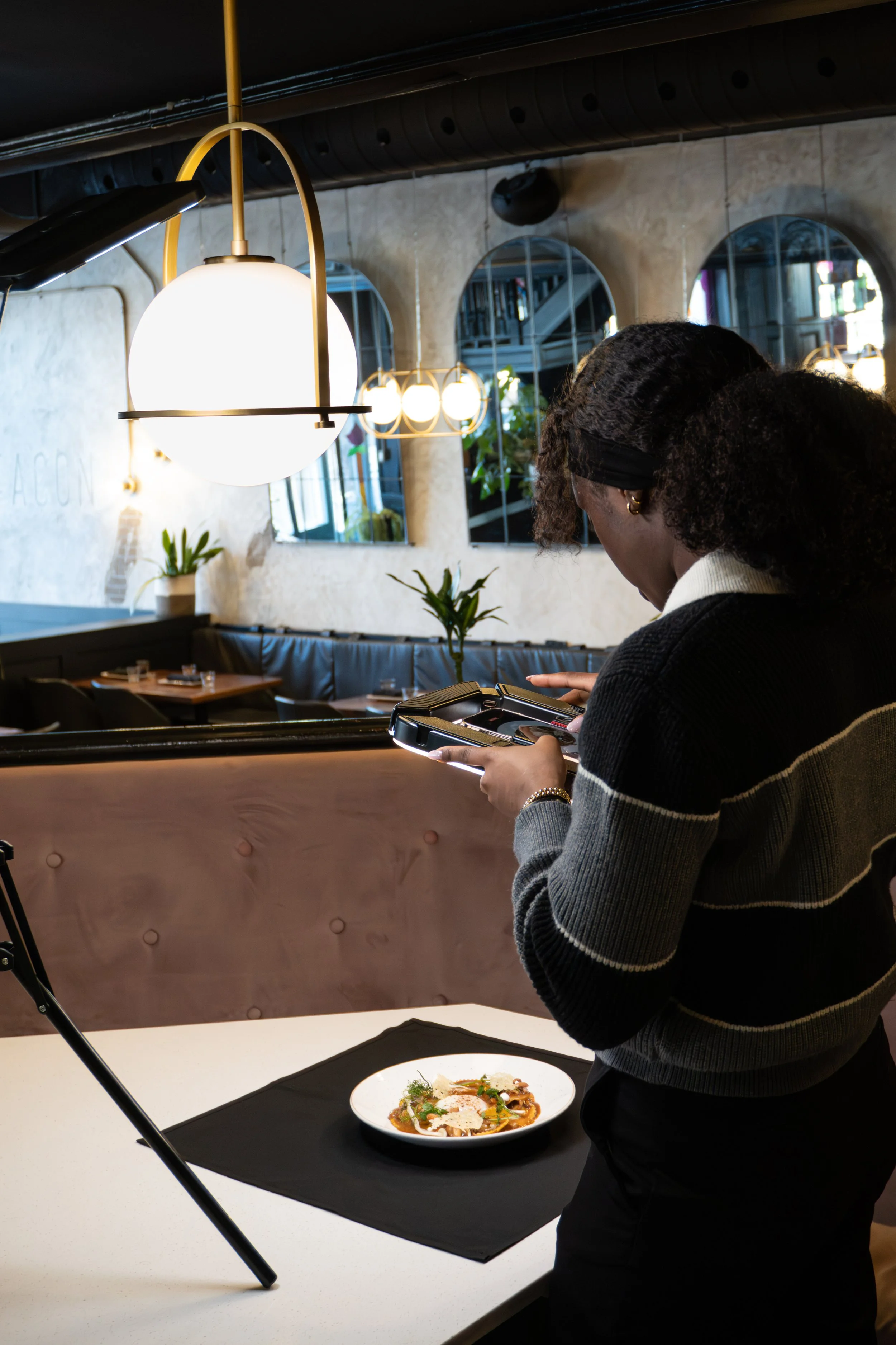 A woman taking a photo of a plated dish of food with a smartphone in a modern restaurant.