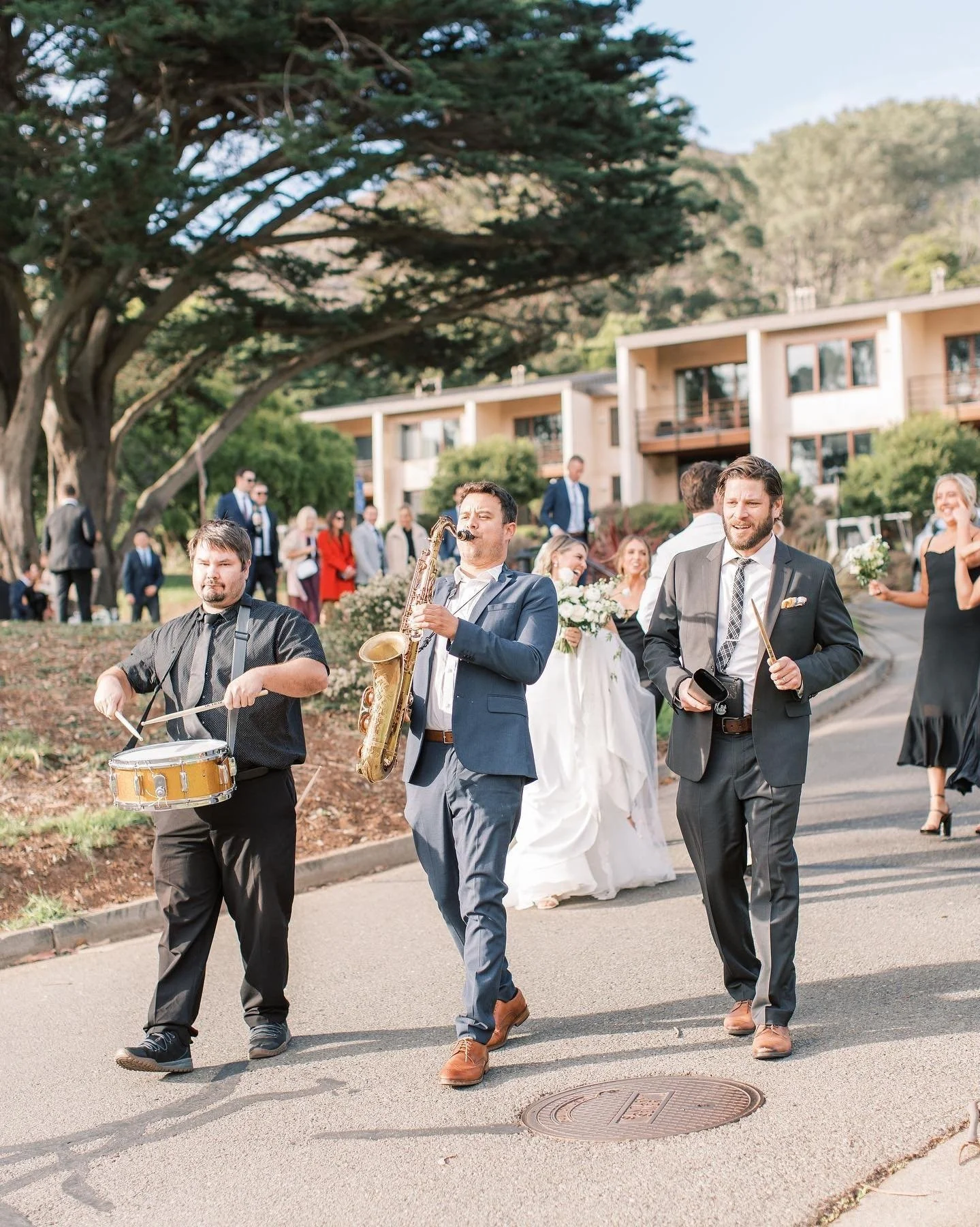 Band playing music at a wedding celebration with the bride and groom in the background.