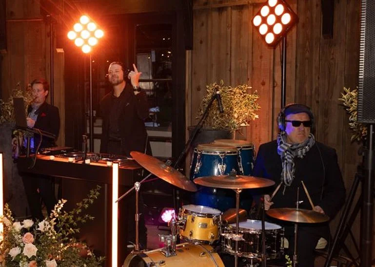 Group of people dancing and playing musical instruments outdoors in a festive setting.