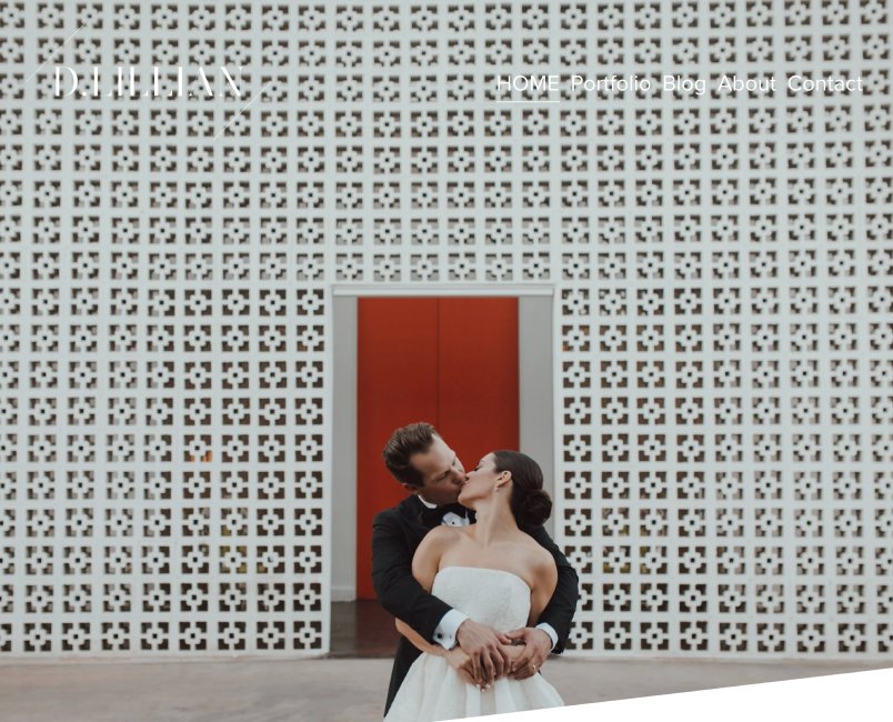 A couple in wedding attire kissing in front of a patterned wall and red door.