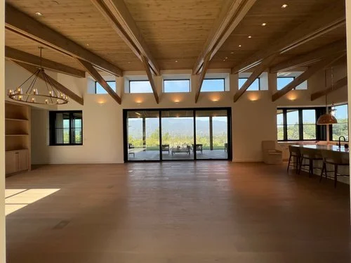 Spacious living area with large sliding glass doors, wooden ceiling beams, and open floor space.