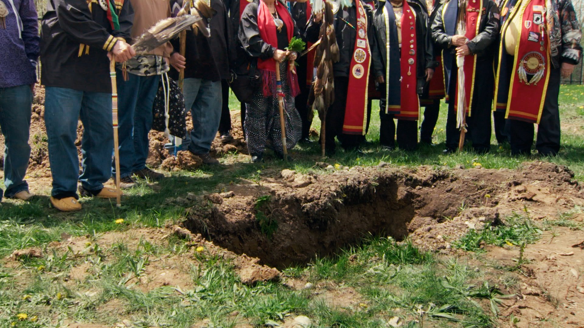 A group of tribal elders stand beside a reburial site.